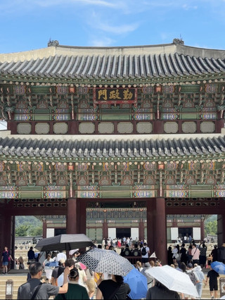 第一次走進景福宮時,最先吸引我目光的不是雄偉的勤政殿,而是位於正殿前方的勤政門。站在門前,彷彿就像走進朝鮮王朝數百年前的重要舞台,每一步都能感受到濃厚的歷史氛圍。勤政門是進入勤政殿前的重要宮門,也是昔日王室舉行重大典禮時的重要通道,平時與典禮期間的使用方式不同,更增添了它的莊嚴感。

我特別喜歡站在勤政門前慢慢欣賞建築細節。屋頂曲線優雅,木構梁柱色彩鮮明,丹青彩繪雖然歷經歲月,依然展現出朝鮮宮殿建築的精緻工藝。從不同角度觀看,都能發現不同的線條與比例之美,即使不懂建築,也會被它的氣勢深深吸引。

穿過勤政門後,眼前豁然開朗,寬闊的庭院一直延伸至勤政殿。站在廣場中央,可以想像過去文武百官依照官階整齊排列,等待國王上朝的景象。當天雖然遊客不少,但整體秩序良好,只要稍微避開人潮,就能拍到很有歷史感的照片。

我很推薦安排上午前往,陽光從正面灑落在宮殿與勤政門上,不僅拍照效果最好,也比較容易感受到建築原本的層次與色彩。如果遇到守門將交接儀式,更能讓整個參觀過程增添不少儀式感。

參觀心得

· 建議預留至少2至3小時,不要只是匆匆拍照離開。
· 勤政門與勤政殿之間的廣場非常值得停留,可以仔細觀察石階、御道及整體布局。
· 上午光線較佳,拍攝宮殿建築更有立體感。
· 若穿著韓服入場,與古宮建築搭配起來更有穿越時空的氛圍。
· 建議搭配導覽或事先了解朝鮮王朝歷史,會更能理解勤政門的重要地位。

這次參觀勤政門最大的收穫,不只是欣賞了一座保存良好的古代宮門,而是真正感受到朝鮮王朝的禮制文化。勤政門雖然不像勤政殿那樣華麗醒目,卻是整個宮殿動線中不可或缺的重要角色。站在門前,望向前方開闊的庭院與巍峨的勤政殿,彷彿能感受到歷代君王與百官曾經在此留下的足跡,也讓我更加體會韓國對歷史文化保存的用心。若有機會再次造訪首爾,我仍然願意放慢腳步,再次走過勤政門,細細欣賞這座承載數百年歷史的宮門,感受它在不同季節、不同光影下所呈現的獨特魅力。