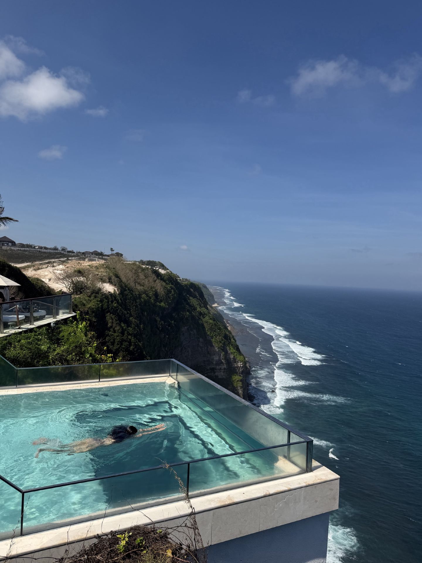 📍 Lokasinya berada di tebing Uluwatu
Ini bukan Beach Club yang aksesnya langsung turun ke pantai, melainkan berada di tebing tinggi di atas Samudra Hindia, menawarkan pemandangan laut yang panoramik. Daya tarik utamanya adalah kolam kaca yang menjorok keluar di atas tebing.
🏊🏻♀️ Daya tarik yang membuat orang datang ke sini — Glass Bottom Sky Pool!
Harus saya akui, kolam di sini cantik sekaligus mendebarkan di saat yang sama 😂
Ini adalah Infinity Pool dengan bagian lantai kaca yang menjorok keluar dari tebing, membuat Anda merasa seperti melayang di atas laut saat berenang.
Kolamnya berada sekitar 160–162 meter di atas permukaan laut, dan bagian yang menjorok dari tebing panjangnya sekitar 6 meter.
Bagi yang takut ketinggian mungkin akan sedikit gemetar, tapi hasil fotonya akan terlihat menakjubkan 📸🥹
🌴 Suasananya sangat menyenangkan
Tempat ini tidak fokus pada pesta seperti beberapa Beach Club di Bali, melainkan lebih ke arah Luxury Day Club.
Ada area untuk duduk bersantai di tepi kolam dengan Daybed, VIP Deck, dan restoran dengan berbagai minuman, cocok untuk bersantai selama beberapa jam tanpa harus terburu-buru.
Di malam hari, suasananya berubah dengan musik yang santai dan lampu-lampu di sekitar pohon palem, sangat ideal untuk menikmati matahari terbenam sambil minum 🍹🌅
🍝 Makanan dan minuman
Mereka menawarkan hidangan internasional seperti
🍕 Pizza
🍝 Pasta
🍔 Burger
🥗 Poke Bowl
🌱 Pilihan Vegan
🍹 Koktail & berbagai minuman
Jadi Anda bisa menghabiskan waktu seharian penuh di Day Club ini, tidak hanya untuk sekadar berfoto lalu pergi.
💰 Biaya masuk
Informasi terbaru untuk tahun 2026 menyatakan bahwa Tiket Masuk Umum sekitar IDR 700.000/orang, sudah termasuk kredit makanan dan minuman sebesar IDR 600.000, akses ke Oneeighty Sky Pool dan handuk, dengan durasi penggunaan sekitar 4 jam.
Namun, harga dan ketentuan dapat berubah tergantung waktu/promosi. Disarankan untuk mengecek kembali dengan pihak pengelola sebelum berkunjung.
📸 Banyak spot foto
Jika Anda datang ke sini, yang perlu disiapkan adalah baju renang + kamera + keberanian 😂
Spot yang tidak boleh dilewatkan adalah
📍 Kolam kaca yang menjorok dari tebing
📍 Pemandangan dari kolam ke arah laut
📍 Area Daybed
📍 Pemandangan sisi tebing
📍 Golden Hour / Matahari Terbenam 🌅
Karena lokasi tebingnya menawarkan pemandangan laut penuh dari hampir setiap sudut.
🤍 Cocok untuk siapa?
Saya rasa tempat ini cocok bagi mereka yang ingin pengalaman “datang ke Bali dan menikmati setidaknya satu hari untuk bersantai dengan mewah.”
Terutama
👩🏻‍❤️‍👨🏻 Pasangan — sangat romantis
👯♀️ Teman-teman — seru untuk berfoto
📸 Content creator — banyak sudut estetis
🌅 Pecinta sunset — pemandangan yang luar biasa
🏊🏻♀️ Pecinta kolam renang — kolam renang adalah bintang utamanya di sini
Tetapi jika Anda mencari Beach Club dengan pantai berpasir dan akses laut langsung, ini mungkin bukan jawabannya karena One Eighty lebih merupakan Cliffside Day Club.
⭐ Ringkasan One Eighty° Beach Club
Jadikan tempat ini salah satu spot wajib kunjung di Uluwatu!
✔️ Pemandangan laut panoramik 🌊
✔️ Glass Bottom Infinity Pool
✔️ Kolam menjorok dari tebing
✔️ Sekitar 160 meter di atas permukaan laut
✔️ Daybed dan VIP Deck
✔️ Restoran dan minuman
✔️ Suasana mewah namun tidak terlalu berisik dengan pesta
✔️ Matahari terbenam yang indah 🌅
✔️ Bagus untuk foto-foto
✔️ Terletak di The Edge Bali
✔️ Buka setiap hari sekitar pukul 10:00–21:00 sesuai informasi saat ini
Jika Anda pergi ke Uluwatu dan ingin hari yang “tidak perlu mengunjungi banyak tempat, cukup bersantai, menikmati pemandangan indah, berenang, berfoto, dan menonton sunset” — One Eighty° pastinya adalah tempat yang wajib Anda tandai 🌴🤍
