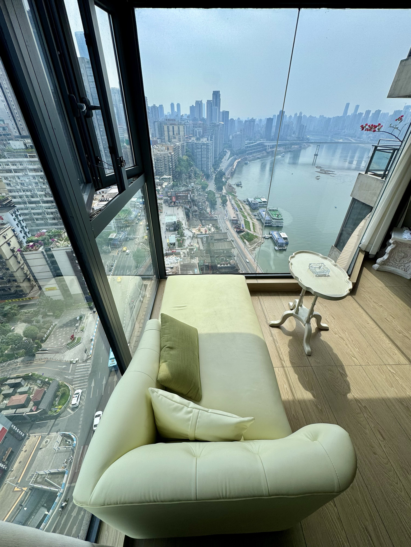 🤯 What a divine setup with a 270° panoramic floor-to-ceiling window!!
Fandiao Boutique Stay (Jiefangbei Hongyadong Branch)
During the day, it’s a healing city view 🌤️
At night, it transforms into the same 8D magical night scene as Hongyadong 🌃
A chaise lounge is set up by the full floor-to-ceiling window, so you can lie down and watch the Chongqing night view and neon-lit cruise ships. This perspective is even better than the Hongyadong viewing platform!!
🌟 The room’s French cream style has truly captured my heart
A soft, fluffy big bed, gentle vintage wallpaper, and a crystal chandelier that sets the perfect atmosphere…
Even the small sofa by the window became my prime spot for photos 📸. Lounging there, feeling the river breeze and sipping milk tea, the leisure of Chongqing is instantly felt!
The best part is the location! Right downstairs is the Hongyadong Folk Custom Area, just a few minutes’ walk to Chongqing Food Street Night Market and the People’s Liberation Monument. No need to squeeze through crowds, and after a tiring day, you can come back to enjoy the entire river view all to yourself. How amazing is that!!