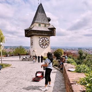 Exploring Graz’s Iconic Uhrturm: Best Views & Local Vibes 🔥🌄  
If you’re in Graz, don’t miss the legendary Uhrturm (clock tower) perched up on Schlossberg hill. This spot delivers major wow-factor panoramas — and it’s epic for travelers of all ages. My favorite moment? Watching a child gaze out over the city, framed by Western-style architecture and lush mountain greenery, even with the weather flipping from cloudy to sunny and rainy. The mix of historic buildings and sleek modern facades is a cool surprise!

Must-See Spot in Graz  
▫️ Uhrturm (Am Schlossberg, 8010 Graz, Austria) — Open all year: 00:00–23:59  
▪️ The climb up Schlossberg is a workout but totally doable; you can use the stairs, take the Schlossbergbahn funicular, or ride the glass lift for awesome city views through the trees.  
▪️ Rain or shine, the scenery’s always Insta-worthy — don’t let the weather hold you back! Graz looks stunning in every mood.

Tips & Tricks:  
▫️ Go early in the day for fewer crowds.
▫️ Bring snacks and water, there’s plenty of space to sit for a picnic with a city backdrop.
▫️ Weather changes quick! Pack an umbrella or light jacket.  
▫️ For families: Kids love the Uhrturm’s huge clock faces & the view from the hilltop!

Getting Around: Graz has solid public transport, but Schlossberg is central so it’s an easy walk. For quick city moves, local buses and trams are efficient.

Foodie Tip: Grab a pastry or coffee at a café near the base of Schlossberg before your climb. The area’s got tasty, local options.

#GrazViews #AustriaTravel #Uhrturm #FamilyExplorer #tripdotcom