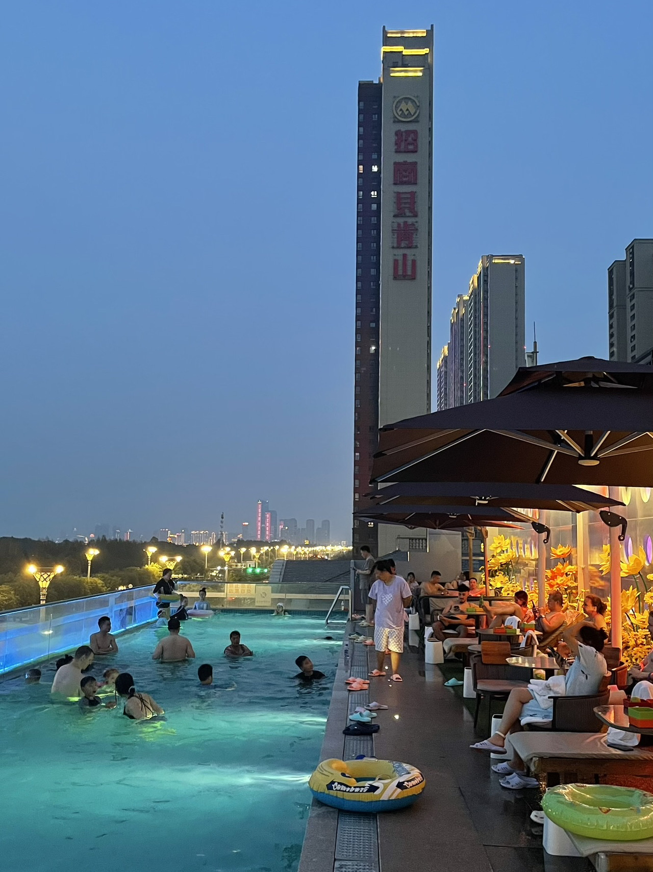The bathhouse complex is called Na Hailan Wanshuihui (保利天珺店)

The bathhouse is located in the convenient Qunli area. It's a 10-15-minute taxi ride from the city center.

The complex has 5 floors.
1st floor - reception and men's area.
2nd floor - massages
3rd floor - relaxation areas and fruit stands
4th floor - restaurant
5th floor - women's area. Children's area with a mini-water park. Rooftop access to the pool and hot tubs.

To enter, you only need a swimsuit; everything else will be provided.

You'll be given slippers upon entry, your shoes will be taken away, and you'll be given a wristband with a number.

Next, proceed to the changing rooms: men's on the first floor, women's on the fifth.
In addition to the lockers where you leave your belongings, the men's area has three large hot pools, a large TV, showers, and a spa area with additional services. Complimentary fruit is also available.
The women's area has no pools, only showers, one sauna, and spa treatments for an additional fee.
The showers are fully stocked: shampoo, conditioner, shower gel, face wash, disposable toothbrushes, various facial products, and hair dryers.

Towels are available as usual. You can also borrow pajamas for the 2nd, 3rd, and 4th floors.

After changing, showering, and putting on a swimsuit, the women's locker room on the 5th floor leads directly to the children's water park, which is adjacent to the rooftop pool and hot tubs.

There are lounge chairs and tables here; if you're lucky, they might be available. You can also bring fruit from the 3rd floor; fruit is included in the entrance fee.

It also offers a beautiful view of the bridge and the city.

Entrance to the complex is 68 yuan for adults and 38 yuan for children 1.0-1.4 m tall. If you take the additional treatment package, the entrance fee is already included, and you only pay one service fee.

The bathhouse is open 24 hours a day, but the rooftop pools are open until approximately 10:30 PM. Fruit is available until 11:00 PM.

🚕 You can get there by taxi
Address: 哈尔滨市道里区友谊西路5245-1号
Name: 那海澜湾水汇 (保利天珺店)