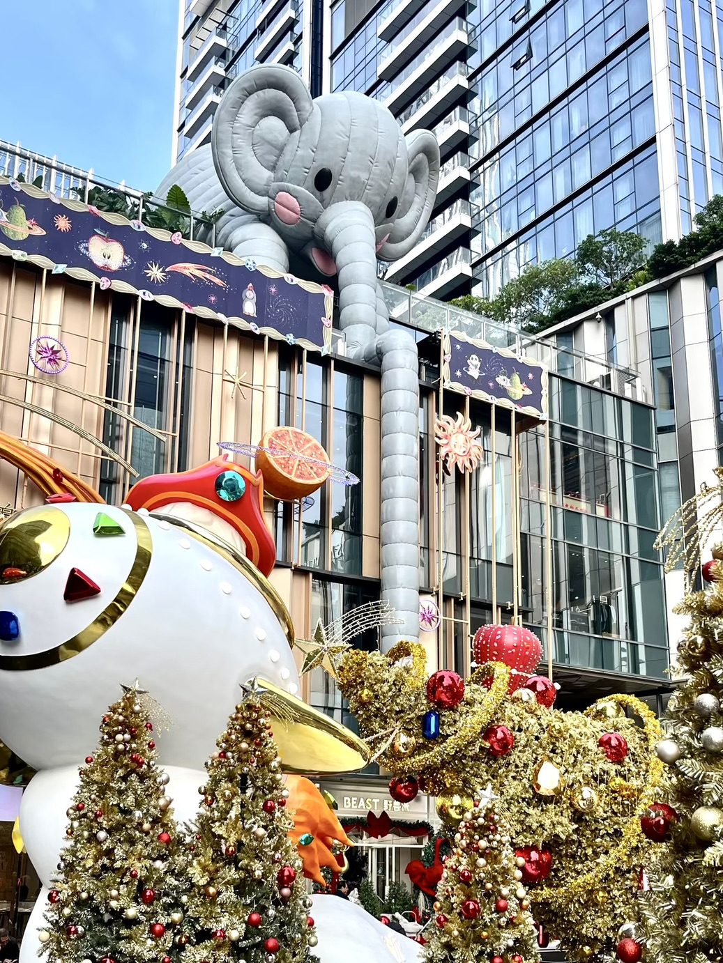 Shenzhen's Christmas wonderland at MixC World is truly unmatched, with a 100% festive atmosphere. This year, the must-visit Christmas installation features a Yeti captain wearing a jeweled pirate hat, piloting a flying ship that carries an entire jeweled Christmas tree. And the tree isn't standing—it's flying! The scene feels like stepping into a fairytale fruit planet, with a carousel glowing warmly under the starry sky, making every photo look like a romantic movie still.

Outfit suggestions: Opt for off-white, red, or Christmas-themed sweaters paired with scarves for a cozy and photogenic look! You'll also encounter many adorable pets, so bring your furry friends along.

Must-visit spots:
- 10-meter-tall Christmas Magic Book House
- 150-meter-long Christmas Starlight Forest High Street
- Experience a romantic snowfall in Shenzhen
- Leon's Bookstore, where an upward shot looks super cool! The cat head inside even moves—it's quite cute.
- Other attractions include the Forest Staircase, Wooden Vintage Station, and Magic Shop.

Tips: It's recommended to visit during the day when it's less crowded, so you won't have to compete for photo spots. While the nighttime ambiance is magical, daytime sunlight offers a different charm for your photos. Besides the Christmas tree exhibition, there's also a Giant Exhibition to explore at MixC World.

Location: MixC World, Shenzhen
Transportation: Direct access from Exit A of Gaoxinyuan Metro Station on Line 1.