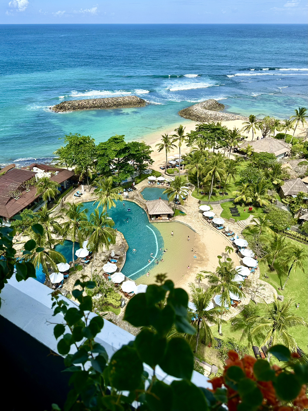 Let me share my impressions of my stay at the Hilton Bali Resort (4 nights, 5 days)
🌦️ When? Late May 2026
The weather was lovely: beautiful clouds at times, occasional rain at night, and bright, sunny days. The southeast breeze was pleasant—neither too hot nor too cold 
· Hotel Price: Very reasonable for a 5-star Hilton. The property is older (which has its perks, as I'll explain below), but the rooms have been renovated. The room was highly comfortable with modern amenities and a great bathroom featuring excellent water pressure in the shower. 
· The balcony is spacious, complete with a cozy daybed and an armchair. Spending time here with a book and a cup of tea is an absolute delight. The ocean view is incredibly soothing
· As for the downsides of the room, there are a few spots that could use a deep clean (for example, the metal fixtures on the ceiling)
· I stayed in a room in the Cliff Tower, which is the closest to the beach and pool. It’s super quick to pop down for a swim or a stroll along the shore. The elevators run smoothly, and two of them are panoramic, offering sweeping ocean views
🌊 Overall Hotel Highlights:
· Breathtaking ocean views! The hotel sits on a cliff overlooking the ocean, with its buildings tiered across several levels. The upper buildings sit quite high, making the views from the lobby and restaurant simply spectacular!
· Expansive grounds: There's plenty of space for a walk or even a jog without ever leaving the property. Because it's an older hotel, the grounds are lush and green, filled with centuries-old trees and vibrant plants 
· You can occasionally spot monkeys roaming around 
· There’s a beautiful temple on the property—a serene spot perfect for yoga or a sunrise/sunset photoshoot. The photos will turn out amazing!
· For fitness enthusiasts: There are tennis courts 🎾 and a gym. It's also incredibly pleasant to take an evening dip in the pool when it's less crowded; the pool stays open until 11:00 PM
· Breakfast 😍 This has to be one of the best breakfasts in Bali! You can grab a table on the terrace overlooking the ocean; 
☕️ Great beverage selection: Coffee and matcha, with plenty of plant-based milk options (almond, coconut, oat). 
🌱 Lots of vegan options: Delicious, naturally made vegan desserts, vegetarian Indian and Turkish dishes, coconut yogurt, almond butter, and more. 
There's a massive selection of muesli, fresh fruits, juices, local Indonesian dishes, plus Chinese, Japanese, Indian, and Western cuisine. They also have an extensive salad and greens bar
I give this breakfast a solid 5 out of 5 points
· For lunch and dinner, you can dine at one of the hotel's on-site restaurants. Several restaurants with different cuisines
· Buffet dinners are hosted outdoors on the hotel grounds, complete with al fresco dining and evening entertainment: local dances, music
· One downside is the breakwaters on the beach. The beach was much nicer before they were installed. In May, the tide still brings in quite a bit of seaweed and debris (this clears up a lot by summer), though the staff does a good job cleaning it up
· Great SPA with private bungalows (but a minor drawback during the day—you can hear music from the pool bar)
· Multiple pools with varying depths
🍀Family-Friendly Features:
· Perfect for traveling with kids: There's a kids' club, and high chairs are provided at breakfast. The grounds are very stroller-friendly
· Kids' pool: Shallow, with a sandy entry and sand around the loungers—making it feel like a seamless extension of the beach
· Since the hotel was built solidly back in the day, the walls are thick and sturdy, meaning rooms are remarkably soundproof
· The service truly lives up to 5-star standards
· The Hilton app is super convenient for making restaurant reservations and snagging hotel discounts
· There’s a grab-and-go cafe with drinks and snacks, where you can pick up salads, sandwiches, and desserts, or just sit here and relax in the AC

Wishing you a wonderful trip! Enjoy your vacation 🍀