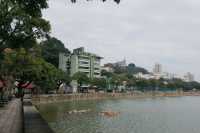 The curved moon over the railing, the tranquil blue lake, the flowing water, the small bridge, and the secluded path.