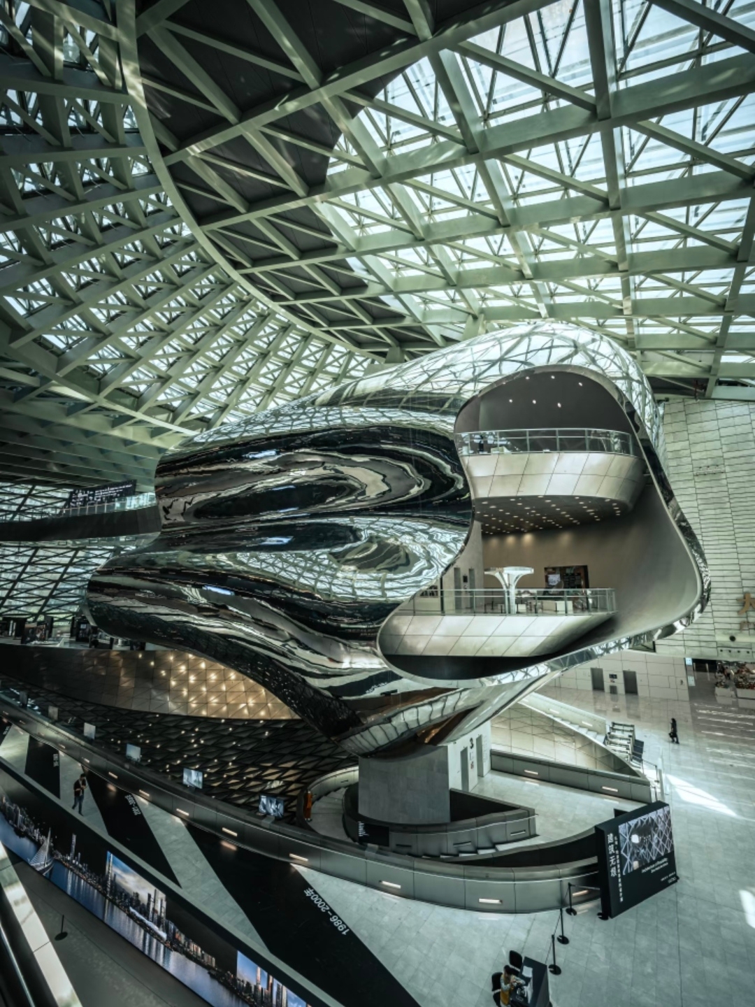 This building designed by Blue Sky Group is itself a moving visual feast. It has no columns, with huge steel structures and glass curtain walls, filling the entire space with a futuristic feel. To capture it well, the key is to find the right angle and lighting.

First, get to know the basics
Address: No. 184 Fuzhong Road, Futian District, Shenzhen
Transportation: Exit A2 of "Children's Palace Station" on Metro Lines 3/4, a 3-minute walk.
Opening Hours: Tuesday to Sunday 10:00-18:00 (last entry at 17:30), closed on Mondays.
Tickets: The building itself is free and no reservation is needed, but recent special exhibitions require tickets.
1. Central Hall: Shoot the "Cloud" Sculpture from Below The huge silver "cloud" sculpture is the soul of the entire building. Standing in the center of the hall, use your phone’s ultra-wide 0.5x lens to shoot upwards, capturing the twisted metal surface and the steel structure lines behind it for the strongest visual impact.

2. Spiral Staircase: Create an "Inception" Effect This is the easiest spot to get great shots. You can shoot downward from upstairs to capture the geometric beauty of the spiral; or shoot upward on the stairs, having a companion walk in the frame to add a storytelling element.

3. Fourth Floor Sky Corridor: Light, Shadow, and Portraits The corridor is an excellent place for light and shadow photography. In the afternoon, sunlight slants in, creating beautiful light and shadow lines on the ground. People can lean on the railing to shoot silhouettes or side profiles, creating a strong atmosphere.

Recommended Ruiya Serviced Apartment Science Museum Branch
Right below the apartment building are the lively Nanyuan Road and Puwei Village, with many local-favorite eateries within walking distance. Here are three recommended places with different styles, all within a 5-minute walk.

Dashujiao Yunnan Cuisine | A Bite Full of Sour and Spicy Hotpot Flavor

This restaurant specializes in authentic Yunnan flavors and is a popular "queue king" nearby. The dishes are full of hotpot aroma; Hani grilled fish and mint stir-fried beef are must-orders for many, sour and spicy to whet the appetite and go well with rice.

Signature Recommendations: Hani Grilled Fish, Mint Leaf Stir-fried Beef, Old Grandma’s Potatoes
Average Cost: About 88 RMB
Address: No. 105 Dongyuan Road, Futian District