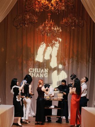 Summer nights in the mountain city, the taste of authenticity
  · Chuanshang Restaurant
"Yujian·Summer Season" 2026 Summer Tasting Banquet
Concluded successfully yesterday amidst candlelight and draped curtains.
Over 40 gourmets, food critics, and senior media professionals attended by invitation,
arriving at the authentic taste of a Chongqing summer in every lingering bite.
The venue featured no screens or projections and no complex interactions,
pouring all the refinement into the plates.
The space was set in black and gold, with curtains draped from above,
while candlelight and crystal chandeliers intertwined to create a deep, warm atmosphere.
This is the philosophy Chuanshang has upheld since its relaunch:
· et the visual serve the palate, and let the sense of ritual serve focus.
The food itself became the sole focus throughout the evening.
🍃 Eating in season, turning local flavors into poetry.
Executive Chef Charlie Yang Caihong
draws inspiration from the vibrant street life,
reinterpreting ordinary flavors with more exquisite ingredients and techniques.
The light pink "rouge" steamed bun, made with dough naturally kneaded with fresh amaranth,
gently opened the summer banquet with the flavors of the mountain city.
🔥 A charcoal-grilled hidden menu item.
Paying tribute to the 20-year dedication of the local snack artisans on Chunsen Road—
Dadong's "Crispy but not greasy" roast duck was sliced on-site,
its golden, crispy skin wrapped around soft, glutinous rice and garnished with sugar and sesame seeds.
The charred aroma of the fat and the subtle sweetness of the rice were released in layers,
condensing the warm, authentic flavors of memory into a single bite.
🍇 Mountains and rivers in a glass, flavors defined.
Chuanshang Chief Sommelier Bara Tao Xiaoxia
outlined a complete sensory journey with 6 fine wines from the Western regions.
From the crispness of Puchang Rkatsiteli to the mellow richness of Tiansai T95 Marselan,
the 6 wines progressed layer by layer, bringing the terroir of the mountains and rivers into the glass and the diverse flavors of Chongqing to the table.
🌿 A promise of a banquet, the "taste" continues.
This was not the end of a dinner,
but another firm step forward for Chuanshang in its mission of "new expressions of local ingredients."
In an era of noise and transience,
Chuanshang has chosen a quieter path—
keeping the spotlight away from the clamor and letting the plate return to the ingredients themselves.