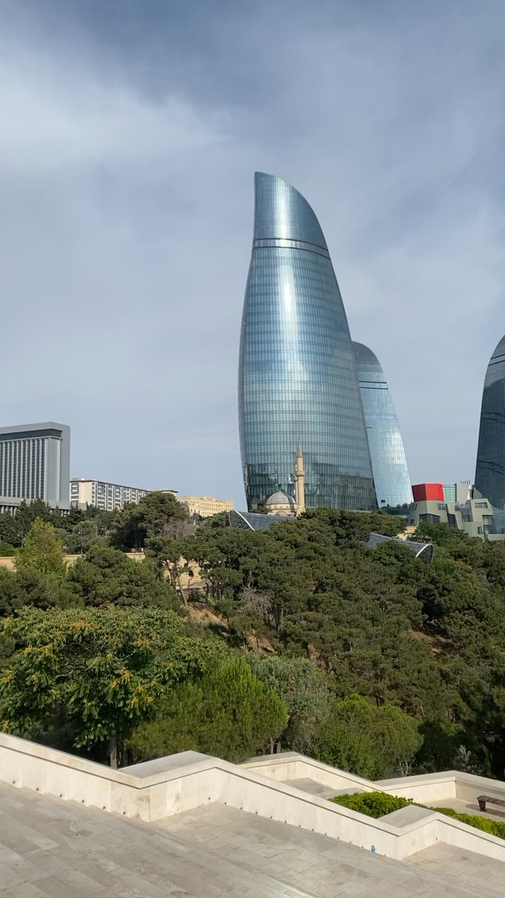 Panoramic view of Baku from a high vantage point, showing the city's mix of modern and historic buildings, including the Flame Towers and Caspian Sea.