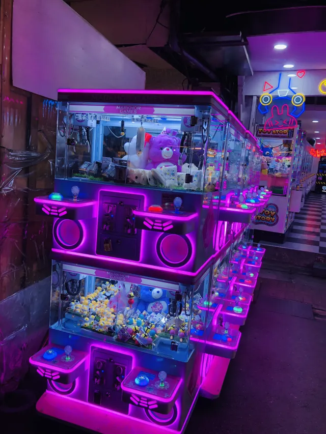 樂華夜市裡的夾娃娃機店，霓虹燈光照亮一整排機台與玩偶