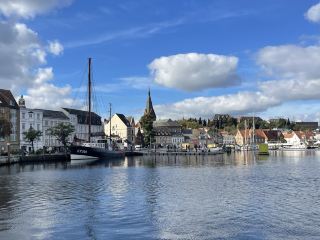 弗倫斯堡(Flensburg)位於德國石勒蘇益格-荷爾斯泰因州最北端,坐落在弗倫斯堡峽灣西岸,距丹麥邊境約2公里,人口約9.9萬。憑藉臨近丹麥的地理位置和麵向波羅的海的港口優勢,很早便發展成為德國與丹麥文化交融的邊境城市,德語與丹麥語在這裡並存,丹麥少數民族擁有自己的學校和文化機構。中世紀以來,海上貿易推動城市發展,航海、造船和商貿成為弗倫斯堡歷史的重要組成部分。今天的老城仍保留著當年商人修建的倉庫、住宅和庭院。此外,德國聯邦機動車管理局(KBA)設於弗倫斯堡,負責全國駕駛資格登記,因此德國交通違章記分俗稱“弗倫斯堡積分”。