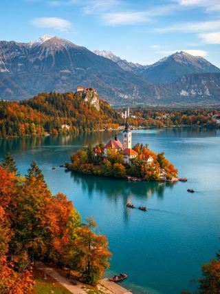Lake Bled, hailed as one of Europe's most beautiful lakes, boasts crystal-clear turquoise waters and a fairytale-like island in its center, perched atop a cliff overlooking the historic Bled Castle. Every autumn, the lakeside forests burst into vibrant colors, creating a breathtaking postcard-perfect scene with the castle and church reflected in the water, a favorite among photographers and couples. Whether strolling along the lakeside, boating on the lake, or gazing out from the castle, you can experience a tranquil and romantic atmosphere.

Recommended Itinerary: Starting from the main entrance of Lake Bled, we suggest a leisurely walk along the lakeside path to enjoy the morning scenery. The entire loop is approximately 6 kilometers and takes about 2 hours at a leisurely pace. Along the way, you'll pass several viewpoints, perfect for taking photos or stopping for a relaxing coffee. We also recommend taking a traditional wooden boat (Pletna) from the west bank pier to the island in the middle of the lake to visit the famous Church of Our Lady of the Assumption. Don't forget to climb the bell tower and ring the bells, as legend says it brings good luck.

Must-Do Activities:

1. Pletna Boat Tour: Purchase tickets at the lakeside pier and experience this unique local mode of transport, getting up close to the small island in the center of the lake.

2. Climb Bled Castle: It's recommended to allow 1 hour for a visit. The castle's exterior is imposing, and the viewpoint offers panoramic views of the entire lake area, making it a perfect spot for photos.

3. Enjoy Bled Cream Cake at a Lakeside Cafe: Don't miss this famous local dessert when visiting Bled; enjoying it with a lake view creates a special atmosphere.

Recommended Photo Spots:

· Benches along the lakeside path for photos of the island and castle reflected in the water.

· Bled Castle Viewpoint: Capture the entire lake and snow-capped mountain backdrop.

· The small pier in front of the clock tower on the island offers stunning lake views.

Travel Tips and Precautions:

1. Recommended to visit in October, when the autumn foliage changes color, creating breathtaking scenery.

2. The lakeside path is suitable for walking or cycling, and there are multiple signs along the way, making it easy to navigate.

3. The island's church requires climbing 99 stone steps; comfortable walking shoes are recommended.

4. Wooden boats are available for unlimited time, but they get very crowded during peak season (October). It's advisable to depart early in the morning to avoid peak tourist times.

5. Lake Bled is open year-round, but the castle and some facilities have specific opening hours. Check in advance to avoid disappointment.

Topics: #LakeBled #SloveniaTravel #AutumnLakeViews #Europe #RomanticLakeIsland