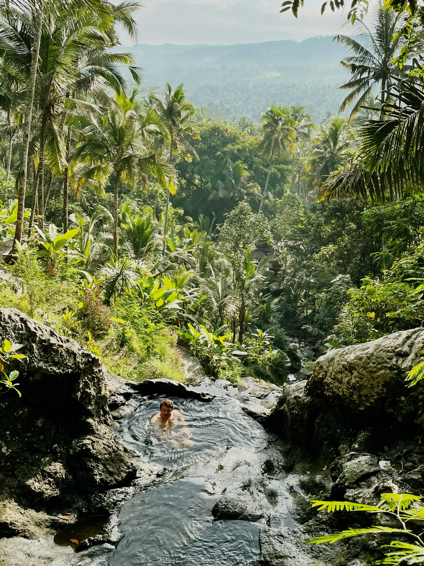 There are places where Bali looks completely different.
Without the crowds of tourists, trendy beach clubs, and endless villas.

Here, there's only jungle, mountains, water, and silence. 🌴

💦 Waterfall and natural pools
Cascades of water form small natural basins where you can stop, swim, and simply enjoy the surrounding nature.

🌿 A real jungle all around
Dense greenery, tropical vegetation, and the feeling of being somewhere far from civilization.

⛰️ A view that makes you want to climb higher
The mountain offers an incredible panorama of green valleys and jungle. It's especially beautiful when there's almost no one around.

📸 A perfect place for photos
There's no need for decoration here—nature has already done everything itself: water, rocks, palm trees, green slopes, and an endless horizon.

🤍 But the main thing here is the atmosphere
Silence. Peace. Humid tropical air. The sound of water instead of music.

And that rare feeling when you're not just visiting a sightseeing destination, but truly disappearing from the ordinary world for a few hours and immersing yourself in nature.

If you want to see a different Bali—green, wild, and almost untouched—be sure to save this location. 🌿

📍 Save this spot for your next trip to Bali.