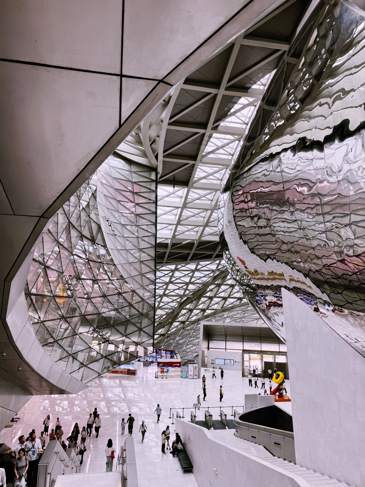 #cultureshock 

I arrived in Shenzhen expecting impressive skyscrapers, but nothing prepared me for the culture shock of standing in front of the brand-new Shenzhen Science & Technology Museum in Guangming Science City. Designed by Zaha Hadid Architects, this building doesn’t belong to 2026—it looks like a colossal interstellar starship that just docked in the middle of a massive park.

· The Cyber-Skin: I noticed the exterior is wrapped in over 90,000 stainless steel panels. They didn’t use a single drop of paint. Instead, a high-tech nano-scale oxide film shifts colors from deep cosmic blue to silver-grey depending on the sun, mimicking auroras and solar flares.
· The Atrium Vortex: I walked into the grand atrium, and it literally pulls you upward. It’s a 33-meter-high fluid capsule connecting 6 floors of mind-bending tech. 
· The Zero-Dollar Entry: The absolute best travel hack? General admission is completely free if you book your entry slot via the official app in advance.

📍 Location: Shenzhen Science & Technology Museum (New Hall)
Address: Guangming Science Park, Guangming District, Shenzhen, China (深圳市光明区光明科学城)