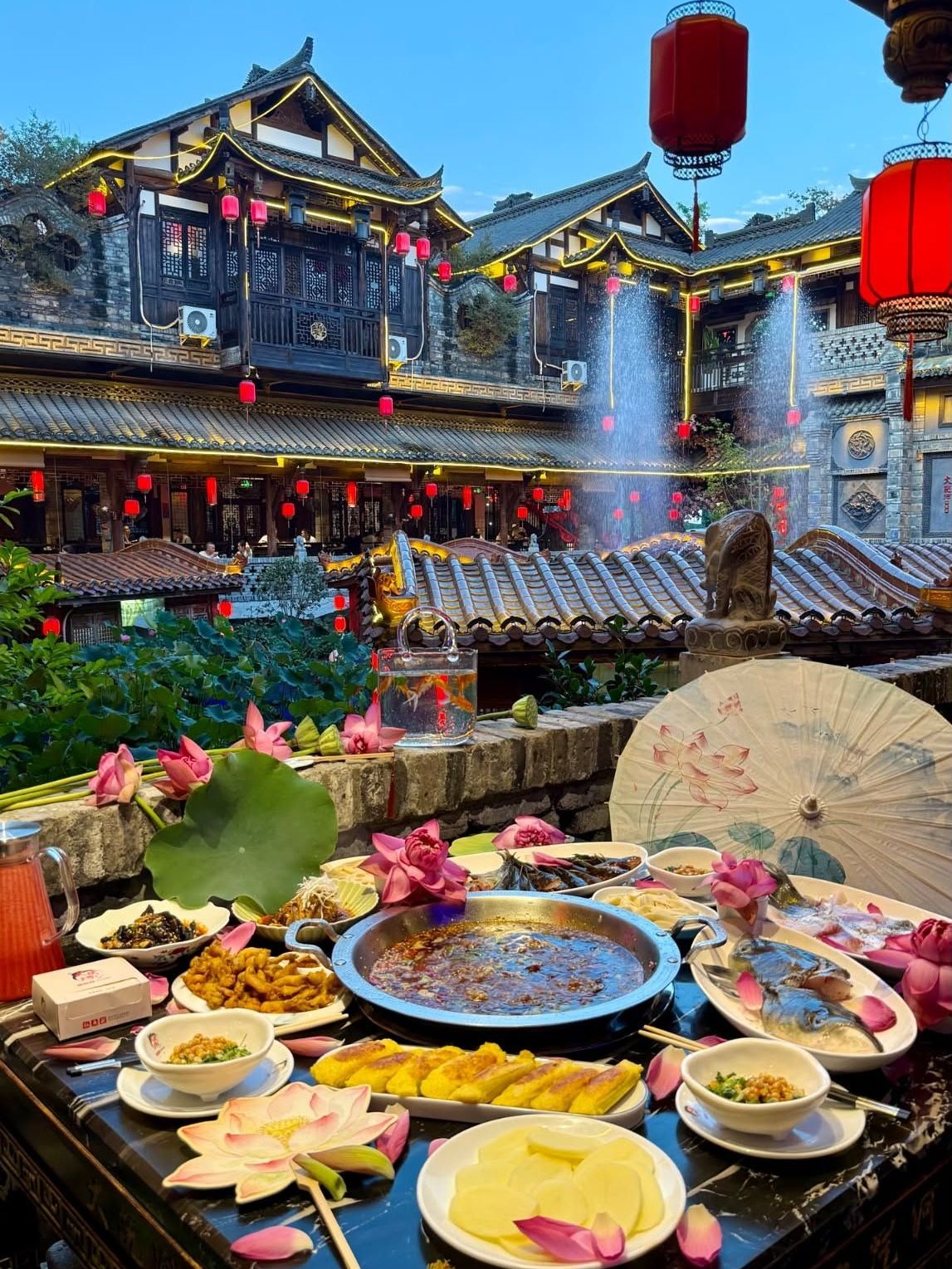 If you're visiting Chengdu and want a hot pot experience that goes way beyond just a meal, I highly recommend this spot. The atmosphere is completely different from your standard hot pot restaurant. You're surrounded by traditional Chinese architecture featuring curved tile roofs and a sea of red lanterns. There’s even a lotus pond, a fountain, and a small pavilion right in the middle of the dining area! The vibe gets even more magical in the evening when the roof lights and lanterns are turned on—it honestly feels like you've stepped straight into a classic Chinese movie. As for the food, it's authentic Chengdu-style hot pot. The broth is incredibly rich and absolutely loaded with spices and chilies. There’s a huge variety of ingredients to choose from, including meats, fish, fried dishes, and snacks. My absolute favorite part is being able to eat while taking in the stunning views around me, as practically every corner is a perfect photo op. They even decorate the tables with lotus flowers and goldfish, making the dining setup look exceptionally beautiful. The cost is roughly 400–500 THB per person, depending on what you order. In my opinion, this is a must-visit restaurant if you want to experience Chengdu hot pot in a truly extraordinary setting. You get fantastic food, a breathtaking Chinese garden ambiance, and tons of amazing photos all in one meal!