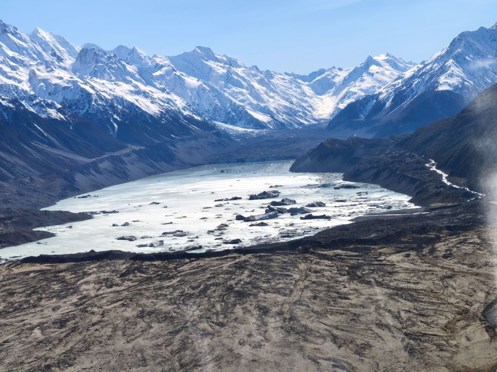 The Mount Cook heli-hike is an unforgettable adventure that combines a thrilling helicopter ride with a guided walk on New Zealand's largest ice mass, the Tasman Glacier. The journey starts with a helicopter flight over Aoraki/Mount Cook National Park. We arrived about 40 minutes earlier as we were advised to reach at least 30 minutes earlier. Before boarding, we were briefed with important information and changed the shoes provided. From the sky, we can see giant snow-covered mountains. Once we landed, we put on special spikes called crampons on our boots so we do not slip. Our guide Tori led us across the ice to explore the frozen landscape filled with blue cave and icy pathways. She is friendly and nice, took some wonderful photos for us. After spending about 1.5 hours exploring, the helicopter picked us up and flew us safely back to the base, leaving us with memories of an incredible alpine world.