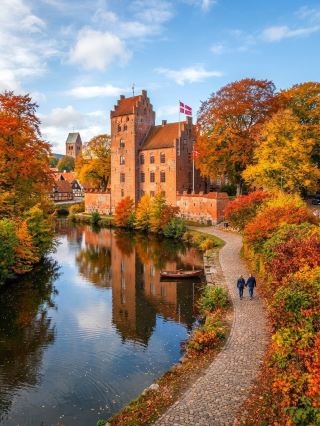 As a classic leisure route in Denmark, the island of Fünger is full of Nordic style and tranquility. This time I specifically chose one of the historical pearls of Funen - Nyborg. Known as the "Old King's City", this small town, the ancient city walls, the guard wall and the red brick church together create a rich historical color, especially suitable for travelers who want to experience the leisurely life of a European town. Strolling through the quaint streets with golden autumn leaves, you are completely immersed in the romance of time travel.

Recommended tour routes:
It is recommended to start in the city center, first to Nyborg Castle to feel the history of the old kingdom of Denmark, grand appearance, very photo-fitting. Afterwards, you can walk slowly along the Volden embankment, which is lined with autumn forests and classical architecture. Remember to pay more attention to the ground, chestnuts will appear quietly in autumn, very treasure hunting feeling, photography plus small prey is especially fun. On the way, you can admire ancient churches, castle moats and antique dwellings and savor Nordic tranquility.

Must-play items and photo spots:
The exterior walls of Nyborg Castle, the Fallen Walk of Volden’s moat, the old church gate, the reflective shadows on both sides of the moat, and the street sporadic traditional Cafe. Every corner is perfect for taking beautiful photos, it's really hipster no matter how you take them.

Game Tips:
1. Comfortable walking shoes are recommended, as the ancient city is a little bumpy.
2. Go in the fall and still have a chance to pick up fresh chestnuts, but be careful to choose the right place, do not enter the private garden range.
3. The weather is cooler, remember to wear enough clothing, especially after nightfall colder.
4. It is recommended to reserve half a day to a day to walk slowly.

Notes:
· Coffee shops and restaurants in the small town of Fiing Island have early opening hours, mostly closed at 9 or 10 pm. If you want to eat, remember to arrange early.
· Most attractions are open free of charge, but visiting the castle is recommended to check the opening hours.
· Public transportation is not frequent, it is recommended to check the bus and train timetable. Self-driving is more convenient and flexible.

Conclusion Topic: It turns out that Denmark has so many quiet town options, slow life journey and Nordic autumn colors do you like?  
#Fien Island #Danishtown #AutumnTravel #SlowLifeEurope #Nordic Style