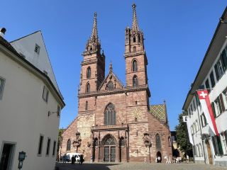 Basel Cathedral (Basler Münster) is the most iconic historical building in Basel, Switzerland, and one of the most famous landmarks along the Rhine River. Construction began in 1019, initially in the Romanesque style. Rebuilt after the 1356 Basel earthquake, it incorporated Gothic architectural elements, resulting in its distinctive appearance today: red sandstone facade, colorful glazed tile roof, and twin spires. The cathedral was once the Basel Cathedral and later became the Church of the Reformed Church of Switzerland. Inside, it preserves exquisite cloisters, crypts, and the tombstone of the famous humanist scholar Erasmus of Rotterdam. The Palatinate (Pfalz) viewpoint behind the cathedral offers panoramic views of the Rhine, the Old Town, and Petit Basel. The surrounding Münsterplatz, with its tranquil environment and many preserved medieval buildings, together with the cathedral, creates a rich historical atmosphere, allowing visitors to fully appreciate Basel's profound cultural heritage and unique charm.
