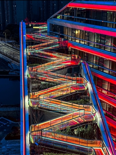 Shanghai never ceases to amaze, and this time it’s the real deal.
“Cyber Rainbow Walkway”
A 750-meter-long elevated walkway, approximately 30 meters above the ground, cutting through the Hongqiao district like a futuristic city. During the day, it serves as a sunny sky terrace with open views, connecting luxury hotels and famous malls for a comfortable stroll.
But at night…
It transforms into a full-on cyberpunk world.
The lights change colors along the entire path, making you feel like you’re walking in a futuristic city. There are giant nest installations, flower-shaped illuminated pathways, and five viewing points offering a full view of the clover-shaped National Exhibition & Convention Center. Every corner is a photo spot—no dead angles.
📍 Location
Huakai Road 35 Lane, Minhang District, Shanghai
Search on the map:
华凯路35号 虹桥天空步道
(Located in Greater Hongqiao / Near National Exhibition & Convention Center)
🚇 How to Get There
• Take Metro Line 2 or 10 to Hongqiao Railway Station, then a short taxi ride.
• If coming from Hongqiao Airport, it’s less than 15 minutes away.
• Perfect for a stopover before your flight or an evening walk.
🌤 Daytime — Enjoy the views, great lighting, and minimalist photography.
🌌 After sunset — Lights start changing colors, full cyberpunk vibes. Best time to visit: 6:30 PM–8:30 PM for the most stunning experience.
💰 Admission Free. Yes, free!!