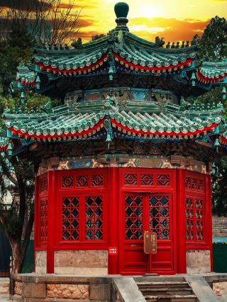 The carved ancient pavilion stands under the setting sun, with colorful tiles and red windows blending perfectly to capture the most beautiful dusk in Daicheng