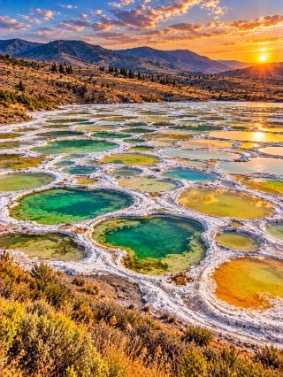 🟢 SEASON 4 EP.3 | Spotted Lake: A bizarre lake with multicolored circles resembling an alien planet's surface! 🇨🇦👽

Can you believe that… there’s a lake on our planet where, during the summer, its surface gradually transforms into hundreds of green, yellow, blue, and white circles, making it look like a giant palette has been placed on Earth! 😱🌈

This is Spotted Lake, originally known as Kliluk, located near Osoyoos, British Columbia, Canada 🇨🇦

This lake is one of the most unique landscapes because its shape changes with the seasons!

🟢 Why is the lake filled with multicolored circles?

The secret lies in minerals and water evaporation!

The lake has a very high concentration of dissolved minerals, especially magnesium sulfate, as well as calcium, sodium, and other mineral compounds.

During the hot and dry summer, a large amount of water evaporates from the lake.

The remaining minerals crystallize and form small, separated basin edges, creating numerous circles across the lake's surface!

🎨 And why are each circle a different color?

The color of the basins depends on the mineral composition, the concentration of dissolved substances, microorganisms, and lighting conditions.

🟢 Some basins appear emerald green.

🟡 Some are yellow or orange.

🔵 Some appear blue or indigo.

⚪ The white edges are often caused by salt deposits and mineral crystals.

When viewed from above, these circles look like surreal patterns on the surface of a planet!

😲 But did you know… this lake doesn't have these spots all year round!

During periods of high water levels, the lake may look like a typical lake.

But as summer arrives and evaporation decreases, the mineral basins become more visible.

The circular patterns are most prominent towards the end of summer, depending on the weather and water levels each year.

🌿 Another wonder is… this is a sacred place for the indigenous people!

Lake Kliluk holds significant cultural and spiritual importance for the people. Syilx/Okanagan has a long history of sanctuary.

The local community holds this lake in high regard as a sacred site, and its minerals have a history of being used in traditional healing practices.

The area is now protected to safeguard both its natural and cultural values.

🚫 Can tourists walk on the lake?

Generally, tourists are not permitted to enter the lake area without permission, as it is a sacred and protected area.

Visitors can enjoy the view from designated and permitted roadside viewing areas, without disturbing the natural environment.

✨ The lake, which looks like colorful circles painted on the earth, is actually the work of minerals, sunlight, and natural water evaporation!

Sometimes nature creates such bizarre patterns that they look like unbelievable works of art! 🌍👽

💬 If you saw this spotted lake from above, would you think it was a real lake 🌊 or the surface of an alien planet 🪐?

#SpottedLake #Canada #AmazingNature