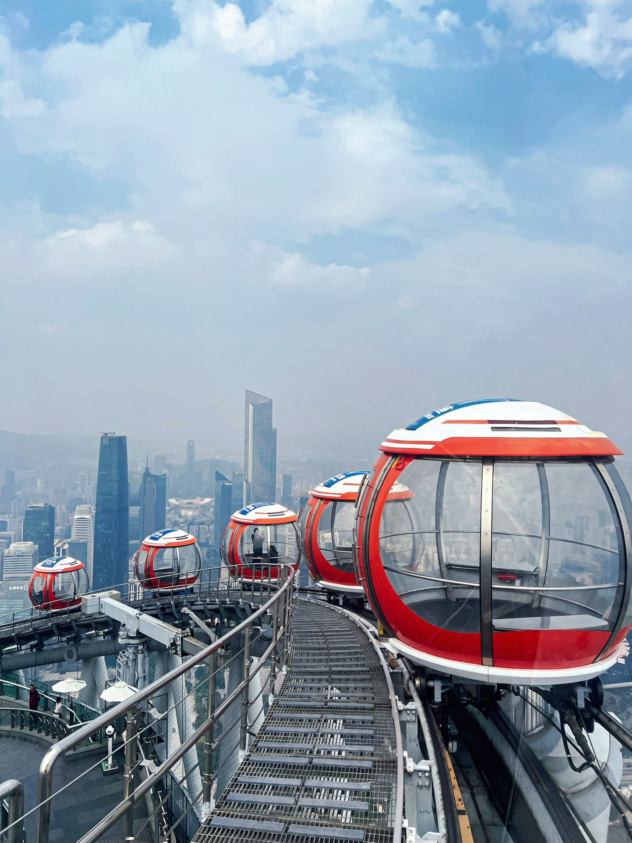 Salah satu momen paling berkesan dari perjalanan saya ke Guangzhou adalah mencoba Bubble Tram di Canton Tower. Sebelumnya saya cuma lihat di foto, tapi pas lihat langsung, rasanya beda banget.

Bubble Tram ini sebenarnya adalah bianglala tertinggi di dunia. Beda dari bianglala biasa, kapsul transparan ini bergerak pelahan mengelilingi puncak Canton Tower, jadi kita bisa menikmati pemandangan kota 360 derajat tanpa terhalang.

Saya sengaja datang ke Canton Tower pas siang hari biar nggak terlalu ramai. Banyak yang bilang mending datang sore atau pas sunset, tapi saya pribadi malah lebih suka suasana tenang di siang hari.

Jangan khawatir soal cuaca. Walaupun di luar panas banget, Bubble Tram ini sudah dilengkapi AC, jadi tetap sejuk dan nyaman selama perjalanan.

Kalau kalian cari pemandangan terbaik, sore hari memang waktu paling pas buat dapat momen transisi dari terang ke sunset. Tapi ya risikonya, menara bakal jauh lebih ramai. Buat saya, suasana yang nggak terlalu padat jauh lebih penting karena bikin pengalaman jadi lebih santai dan rileks.