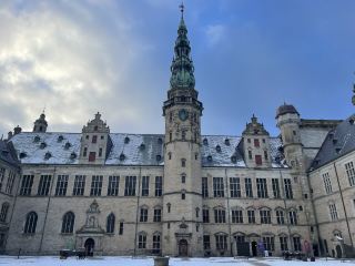 克倫堡宮(Kronborg)位於丹麥東北部赫爾辛格市(Helsingør),距離首都哥本哈根約45公里,坐落於厄勒海峽(Øresund)最狹窄處,與瑞典赫爾辛堡市(Helsingborg)隔海相望,地理位置極具戰略意義。15世紀初,丹麥國王埃裡克七世在此修建了名為“克羅根堡”(Krogen)的要塞,用以控制海峽航道並向過往船隻徵收“厄勒海峽通行稅”。16世紀後期,國王腓特烈二世將其改建為宏偉的文藝復興風格王室城堡,即今日的克倫堡宮。18至19世紀期間,克倫堡宮曾長期作為軍營,並一度兼作監獄。克倫堡宮被公認為莎士比亞《哈姆雷特》中“埃爾西諾城堡”的原型,因此成為世界文學史上的重要地標。2000年,克倫堡宮被聯合國教科文組織列入《世界遺產名錄》,現為丹麥最重要的文化遺產和旅遊景點之一。