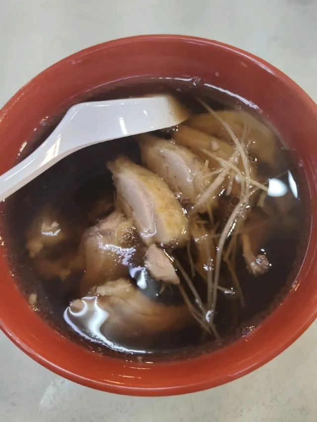 夜市攤上冒著熱氣的麻油雞湯,湯色深、加了老薑與雞肉塊