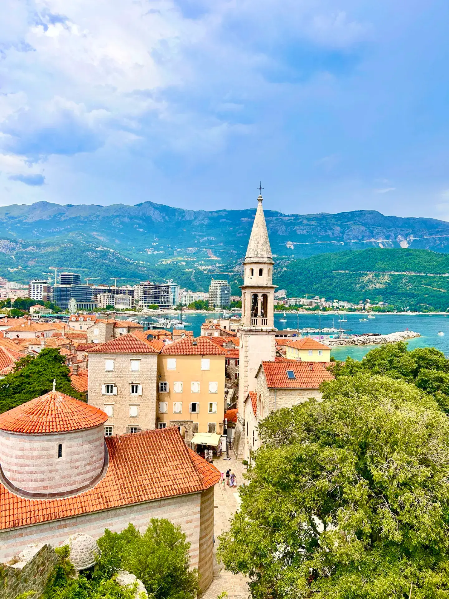 🏛️ Budva Old Town: A Medieval Labyrinth by the Sea

Budva's Old Town (Stari Grad) is the historic heart of the Montenegrin resort capital, located on a small peninsula and surrounded by mighty fortified walls. With over 2,500 years of history, it is considered one of the jewels of the Adriatic coast.

🗺️ What to See

Fortress Walls and Citadel
The 450-meter-long walls were built by the Venetians in the 15th century to protect against Turkish raids. The Citadel (Kaštel) is the highest point in the city, founded in the 9th century. Today, it houses a museum, a library, and an observation deck with panoramic views of the Budva Riviera. Entrance to the Citadel costs approximately 6 euros.

Church Square
Three churches of different eras and denominations coexist in one square:

The Cathedral of St. John the Baptist (7th century) is the oldest Catholic church, its bell tower visible from anywhere in the city. Inside is the miraculous icon of Our Lady of Budva.
The Church of the Holy Trinity (1804) is an Orthodox church in the Byzantine style with a beautiful iconostasis.
The Church of Santa Maria in Punta (840) is the oldest church built into the defensive wall.
The Archaeological Museum
Housed in a four-story building in the Old Town, its collection includes artifacts from antiquity to the Middle Ages, including Roman mosaics and Illyrian finds. Of particular interest are the items from the excavations of the Roman necropolis discovered during the construction of the Avala Hotel in 1936.

"Door to the Sea"
One of the most mysterious landmarks is the Eastern Gate, which leads directly to the sea. Its purpose remains a mystery. It's also worth finding a small "secret gate" through which you can access the small pebble beaches at the foot of the walls.

Roman Ruins
Fragments of ancient heritage have been preserved in the Old Town:

A 1st-century Roman altar with the inscription "Vinicia Pavlina" in one of the squares
Ruins of the Roman Villa Urbana with columns and capitals
Foundations of ancient buildings near the Prego store on Njegoševa Street
✨ Legends and Symbols

The legend of the two fish is the main symbol of Budva. According to legend, lovers Elena and Marko, not receiving a blessing for their marriage, threw themselves off the cliffs into the sea and turned into two fish, remaining together forever. A stone image of two intertwined fish is embedded in the wall of the Citadel—it is believed that touching it makes love strong and eternal.

The origin of the name is associated with the ancient Greek word "bous" (ox)—according to legend, the city was founded by Cadmus, exiled from Thebes, who arrived on the shore on a team of oxen.

🎭 Atmosphere and Life

The Old Town is not a museum, but a living space. The narrow cobbled streets are lined with shops, galleries, cafes, and restaurants, while the upper floors are home to local residents or apartments for rent to tourists. Cultural festivals, concerts, and theatrical performances are regularly held here.

💡 Practical Tips

Time for a visit: Allow 5-6 hours for a full immersion. The best time to visit is May-June or September-October, when the weather is pleasant and there are fewer tourists.
Shoes: The streets are cobblestoned, so comfortable, non-slip shoes are a must.
Best photos: At sunset, when the walls turn golden and the sea shimmers blue.
Food: Try fresh seafood, local pršut (cured ham), and Montenegrin Vranac wine.
Budva's Old Town is the perfect blend of history, architecture, and Mediterranean charm, where every stone holds centuries-old secrets. #budva #budvaoldtown #budvaviewctagnt #montenegrotravel #montenegroviews