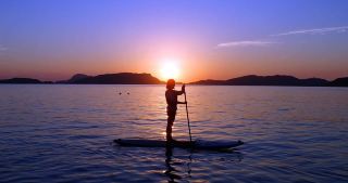 พายเรือแพดเดิลบอร์ดเพื่อไล่ตามชมพระอาทิตย์ตกดินอันงดงามเหนือทะเลสาบเครามะบลู