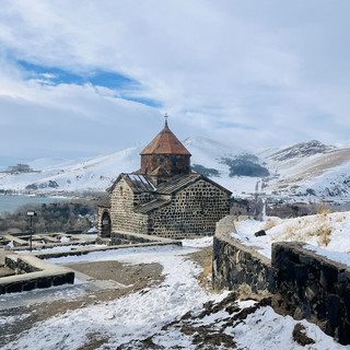 Lake Sevan in Winter: A Pure White World. The mirror-like lake reflects the mountains and clear sky, waves crash against the snow-covered wooden bridge, and towering snow-capped peaks surround it. Especially.