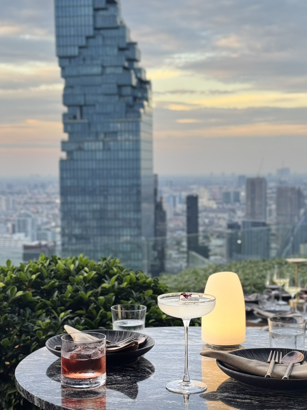 There are places you visit for the food, and then there are places you visit for the experience.

Le Du Kaan in Bangkok turned out to be exactly the latter for me.

We arrived around 5:30 PM, which was the absolute perfect time. At first, the city was bathed in a soft evening glow. Then, the sky started painting itself in hues of pink and gold, and just an hour later, all of Bangkok transformed into an endless sea of lights.

The main reason to come here is, without a doubt, the view. The iconic MahaNakhon skyscraper towers right in front of you, while a seemingly endless city panorama unfolds all around.

The menu isn't the most extensive, but everything we tried was excellent. The cocktails were great, too. Honestly, though, it's worth coming here purely for the view alone.

If you're planning a visit to Le Du Kaan, I highly recommend booking a table in advance and getting there before sunset. This way, you get to experience Bangkok in three different vibes: daytime, sunset, and nighttime.

Another thing I absolutely loved was the relaxed, ultra-comfortable atmosphere, complete with a great DJ set.

It’s evenings like this that make me love this city so much ❤️

 