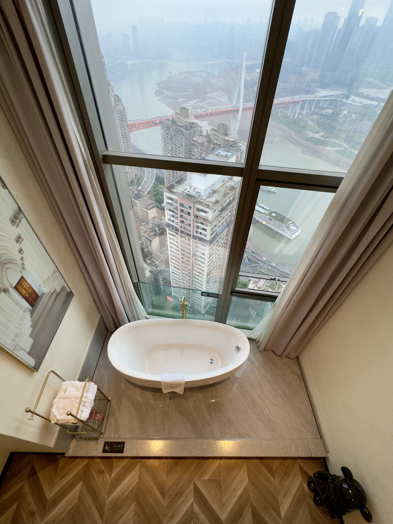 When visiting Chongqing, whatever you do, don't settle for an ordinary river-view room! Hidden high above downtown Yuzhong, this panoramic sky-high sanctuary is the ultimate romantic getaway in the Fog City—a true insider's choice you'll never forget after just one stay. 🌉
Perched right in Chongqing's most bustling prime location, you step out straight into the city's iconic landmarks. Claiming the absolute best high-altitude vantage point with zero buildings blocking your sight, it offers a legit 270-degree sweeping river panorama. The stunning convergence of the Jialing and Yangtze Rivers, the majestic silhouette of the Qiansimen Bridge, and the rolling skyline of the mountain city—all right before your eyes.
In the early morning, rolling mist covers the river, turning the whole city into a living traditional ink painting. In the afternoon, the sun sparkles over the water as cruise ships slowly pass by, creating ripples that instantly soothe the soul. Come sunset, the sky and river are painted in warm tangerine hues, taking the vibes to the absolute max. And when night falls and the lights go on, the neon signs on both riverbanks light up together—the surrounding landmarks, the warm glow of Hongya Cave, and the streams of headlights along the riverside are all caught in a single glance.
No need to brave the crowds outside; just laying in bed gives you exclusive access to Chongqing's top-tier nightscapes. The whole scene feels straight out of Spirited Away—every casual snap is a cinematic masterpiece.
The apartment itself features a duplex loft design, offering an incredibly spacious, airy, and unconfined feel. The decor leans into a gentle, accessible luxury aesthetic, with a muted color palette matched perfectly by exquisite furnishings, warm lighting, and natural wood textures that instantly elevate the vibe. Every single corner is thoughtfully arranged—no need to force poses or hunt for angles, a casual snap is enough to break your Instagram and social feeds with a 100% aesthetic hit rate.
The layout is phenomenal, brilliantly separating the active and restful areas across the two floors. Downstairs is a massive lounge area fully equipped with a plush sofa, floor-to-ceiling windows, and a giant projector screen. Sink into the couch to binge-watch your favorite shows, pull the curtains, and it instantly transforms into a private high-altitude cinema—perfectly cozy whether for a romantic date or a hangout with your besties. Upstairs is a quiet sleep zone with ridiculously soft, comfy bedding and excellent blackout curtains. Falling asleep to the river view and waking up with the starlight is so relaxing it cures all your travel fatigue.
The little details are super thoughtful: the bathroom has spotless dry/wet separation, toiletries are fully stocked, there's plenty of storage, and the lighting throughout is soft and easy on the eyes. Balancing gorgeous aesthetics with real practicality, staying here feels just as comfy as being at home, with none of the usual alienation of staying in a hotel.
The location is completely unbeatable. It's just a short walk to the Jiefangbei shopping district, Hongya Cave, Yangtze River Cableway, and Liangjiang Piers. Right outside your door is the bustling foodie heaven—authentic hotpot, local noodles, and Jianghu cuisine are just steps away.
No need to wake up early to catch a bus, no need to detour for transfers; wherever you want to explore, it's super convenient and saves tons of time.
Whether it's a couple's honeymoon, a photo-taking trip with the girls, a family vacation, or a laid-back luxury getaway, this place is absolutely perfect. It captures Chongqing's river views, local street life, romantic vibes, and city bustle all in one go.
When visiting Chongqing, staying at this sky-high river-view spot is the only way to truly experience the one-of-a-kind romance of the Fog City ✨
