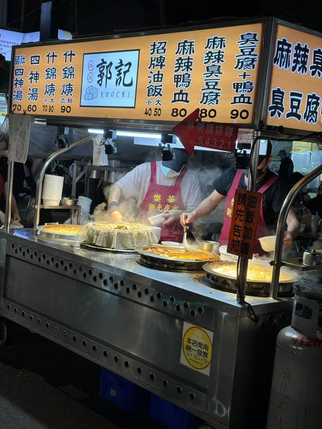 樂華觀光夜市的攤位實景,兩位員工穿著紅色圍裙在蒸氣中備餐,攤前掛著外帶請排隊的告示