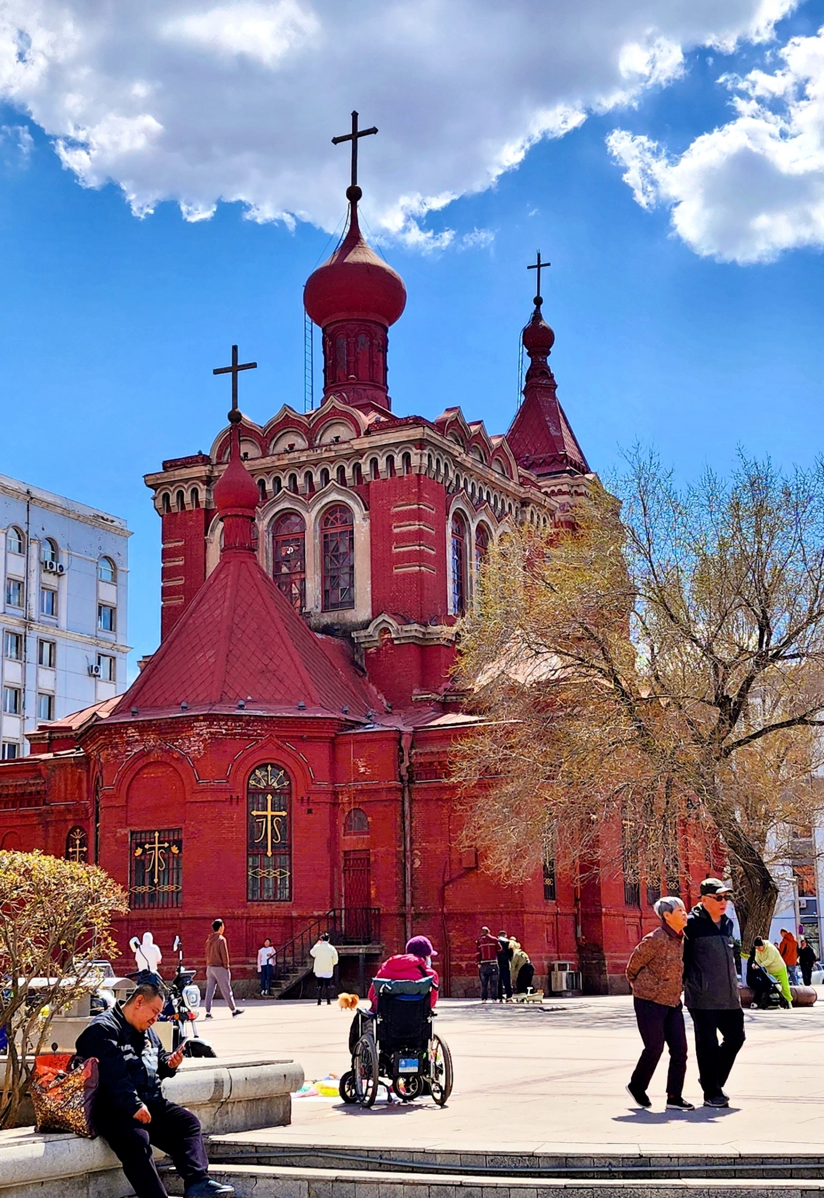 Starting from the Church of the Protection of the Holy Virgin on East Dazhi Street, a 30-minute walk brings you to the intersection of Gexin Street and Shike Street—where St. Alexeyev Church quietly stands. Though not as famous as Saint Sophia Cathedral, its exquisite and delicate appearance leaves a lasting impression. The red walls reflect the domes, blending exotic charm with the texture of time hidden within the streets, with every detail exuding a unique charm.
📍 Location: No. 47 Shike Street, Nangang District (at the intersection with Gexin Street)
🛕 Denomination: Originally Eastern Orthodox, now Roman Catholic
⏳ Construction: Started in 1931, completed in 1935 📮
📮 Current status: Protected cultural relic of Heilongjiang Province, active religious site
This is a typical Russian Baroque-style building, featuring exposed red bricks paired with pristine white relief lines, bright yet elegant in color. Its iconic onion-shaped domes are rounded and full, the staggered tent-style bell tower is tall and graceful, and the facade carvings are delicate without being overly complex, making it especially photogenic against the blue sky.
Its predecessor was relocated and rebuilt by Russian expatriates, and despite the passage of time, it remains well preserved. There are no crowded tourist groups here, only quiet streets and swaying tree shadows. Strolling around the square feels like being in a peaceful European town, where time slows down and softens. Sunlight brushes over the red walls and domes, with every detail telling the unique story of Harbin’s expatriate history and architectural aesthetics.
🌟 From the prayers of the Eastern Orthodox to the hymns of the Roman Catholic Church, every red brick of this church is engraved with stories of wandering, perseverance, and integration. It is a symbol of the Russian expatriates’ nostalgia, a witness to historical changes, and the gentlest footnote to Harbin’s title as the “City of Churches.” The building speaks silently but tells the city’s unique tolerance and romance through a century of time.
📌 Travel Tips
· The church is located next to Gexin Square and is locally known as the “Gexin Church.” The environment is quiet and serene, within walking distance to Gogol Street, making it ideal for a combined tour with the churches on East Dazhi Street;
· The exterior boasts strong exotic beauty, perfect for outdoor photography, but the interior is not open to the public casually;
· Best time for photos: 3:00 PM–6:00 PM, when the setting sun casts rich layers of light and shadow on the red bricks and domes;
· The surrounding area is full of local life, allowing visitors to appreciate both the beauty of historic architecture and the authentic local atmosphere, making it a hidden gem for cultural exploration in Harbin.