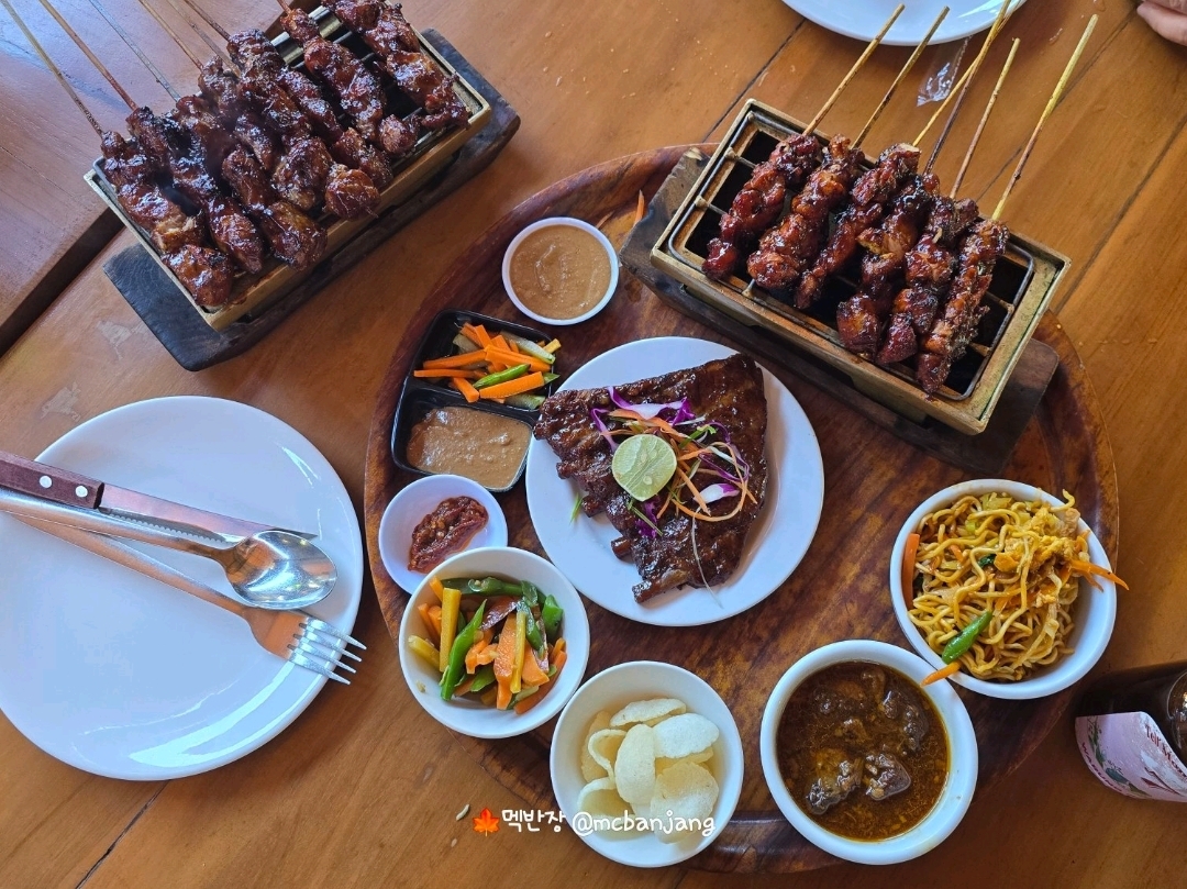 Hello, this is Mexbanjang saying hello.

Warung Nia is one of the must-visit restaurants for your trip to Bali. It is so famous for its Balinese-style BBQ pork ribs and satay that it is loved by both locals and tourists. It has very high ratings from travelers and is consistently cited as a representative restaurant in Seminyak.

Finding the best pork ribs of my life in Bali!

I’m going to share my honest review of Warung Nia, a famous restaurant in Seminyak.

📍 One of the things I looked forward to most while preparing for my trip to Bali was the local food.

While Nasi Goreng and Mie Goreng are great, I heard many times that BBQ pork ribs are one of the dishes you "must eat when you go to Bali." While searching for various restaurants, the place recommended the most was Warung Nia!

Located in the heart of Seminyak, it was convenient to visit after enjoying shopping, and the fact that it is a restaurant loved by locals and tourists for a long time further heightened my expectations.

Upon arriving at the restaurant, I was first greeted by the warm atmosphere characteristic of Bali. While it feels more like a comfortable local eatery than a fancy restaurant, the immaculately maintained space makes it a comfortable place to visit with family, a partner, or friends.

📍 The menu I ordered was the restaurant's signature dish: BBQ Pork Ribs. Satay!

The pork ribs arrived shortly after, and they made my mouth water the moment I saw them. They were generously coated in glossy BBQ sauce, and the subtle charcoal aroma heightened my anticipation.

📍 The moment I took a bite, I immediately understood why this place is famous.

The outside was coated in a sweet and rich BBQ sauce, but the meat inside was incredibly tender. The meat separated naturally from the bone with almost no need for a knife, and the savory yet sweet sauce had soaked into the meat so well that I kept reaching for more even without rice.

📍 The Chicken Satay I ordered alongside it was also satisfying. Pairing the savory peanut sauce with the chicken, which had a lively charcoal aroma, allowed me to truly experience the unique flavors of Indonesia.

🔥Another charm of Warung Nia is its price.

Although it is located in the middle of a famous tourist spot, considering the quality and portion size of the food, it was quite satisfying.

As I left after finishing my meal, I naturally thought, "I must come back here next time I visit Bali."

📌MexBanjang's TIP

✔ The signature dish is BBQ Pork Ribs.

✔ Satisfaction is even higher if you order it with Chicken Satay.

✔ It is busier during dinner than lunch, so visiting a little early or making a reservation is recommended.

✔ Visit as part of a course that includes shopping in Seminyak.

💎Overall Review

If you are looking for a great pork rib restaurant in Bali, Warung Nia is a choice you won't regret.

Tender pork ribs, carefully grilled satay, and the comfortable atmosphere unique to Bali. It was a satisfying meal, enough to be the most memorable one of this trip.

If you want to experience the true taste of Bali, I highly recommend visiting Warung Nia in Seminyak.❤️❤️😁😁

#McBanjang #mcbanjang #McBanjangFoodieTravelogue #WarungNia #warungnia #BaliSeMinyakFood #BaliLocalFood #BaliBestValueFood