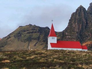 Vík í Mýrdal is a remote seafront village in south Iceland. It sits in the shadow of Mýrdalsjökull glacier, which covers the Katla volcano. Reyniskirkja is a wooden church dating to 1929. Reynisfjara beach has black pebbles, basalt columns and the Reynisdrangar offshore rock formations. The cliffs of Reynisfjall mountain are home to seabirds such as puffins. Just west, the Dyrhólaey peninsula has a large rock arch.