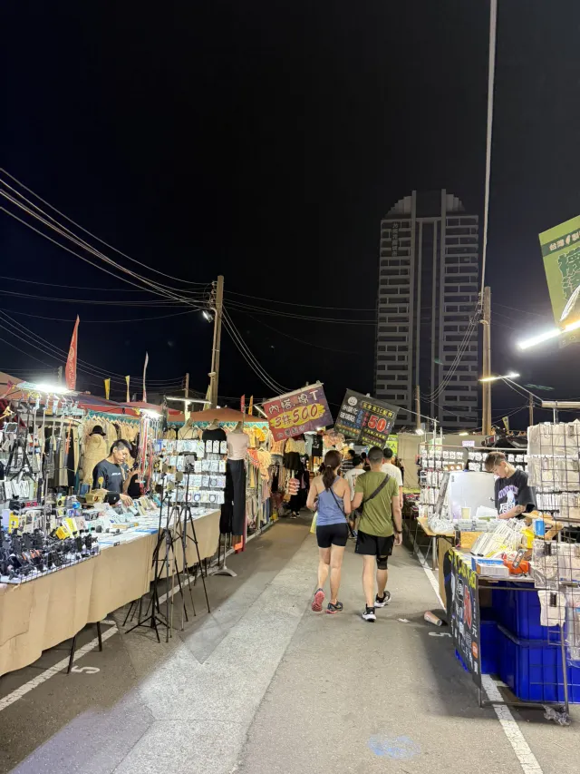 花園夜市西側走道,兩旁是服飾與生活雜貨攤位,後方可見台南市區大樓