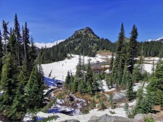 July in the mountains of the Pacific Northwest—snow caps the peaks and the lakes glisten perfectly.