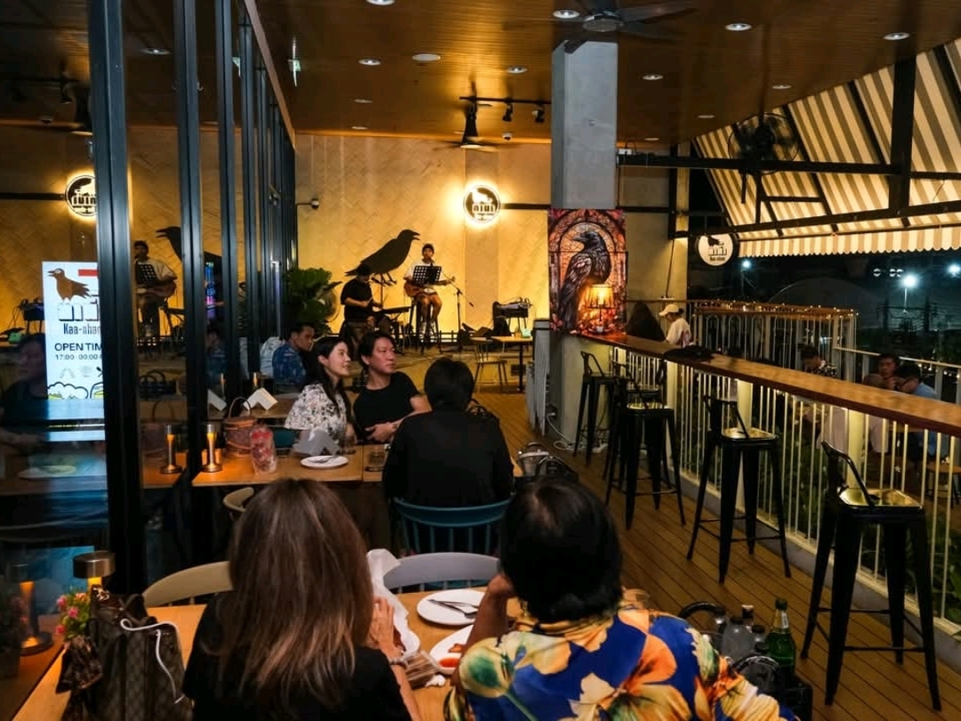 "Kaa-Nham" is a cozy little bar tucked away in Ying Charoen Square. Despite its size, it doesn't feel cramped. The bar offers a balcony view that gives off a rooftop vibe, making it a perfect spot to relax. They serve a variety of delicious drinks and food, and you can enjoy live music up close. The songs are great, and the singers are friendly and approachable.

Overall, this bar is ideal for those who love to chill and soak in the atmosphere. The cool breeze makes it comfortable to sit and unwind. After a long day at work, you can drop by to hang out with friends. It's conveniently located near BTS Saphan Mai station, or if you're driving, you can park at the market nearby. Every corner of this place is Instagram-worthy, with beautiful views for photos. If you visit after 9 PM, the interior might be a bit dim, but you can head up to the second floor.

🏪 Kaa-Nham Bar
📌 Location: Balcony, 2nd Floor, Ying Charoen Square
https://maps.app.goo.gl/HeNnYtGxhtKZu57U9

⏰ Opening Hours: 5:00 PM – 12:00 AM