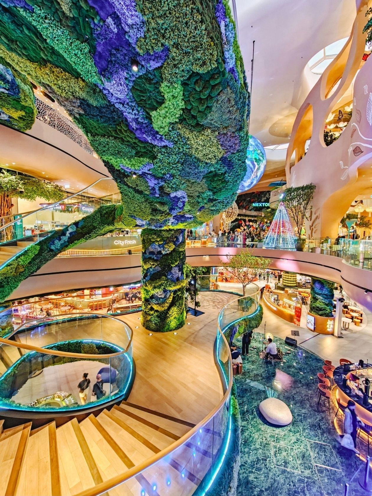 Nơi trú ẩn khỏi mưa và chụp ảnh đẹp nhất ở Bangkok.

Cuối tháng 9 ở Bangkok là thời điểm mà trời có thể đổ mưa chỉ trong năm phút. Bạn đang đứng ngoài trời, không hề lường trước điều gì, và đột nhiên một bức tường nước ập xuống. Ô dù không thể cứu bạn. Bạn không thể gọi taxi. Và chính lúc này, bạn sẽ hiểu tại sao những du khách dày dạn kinh nghiệm lại lên kế hoạch cho hành trình của mình xoay quanh một địa điểm này trong mùa mưa.

Siam Paragon.

Đây không chỉ là một trung tâm mua sắm. Đó là một nơi trú ẩn mở cửa từ 10 giờ sáng đến 10 giờ tối và được kết nối trực tiếp với ga BTS Siam thông qua một cầu vượt, không cần phải bước ra ngoài trời một bước nào. Bạn xuống tàu ở ga Siam, đi bộ qua một cây cầu có mái che, và thấy mình đang ở bên trong. Mưa sẽ ở bên ngoài.

Nhưng nơi này còn có một vai trò thứ hai. Siam Paragon cũng là một trong những địa điểm chụp ảnh đẹp nhất ở Bangkok. Và không chỉ vì nó có một bức tường Instagram duy nhất. Bởi vì mọi thứ ở đây đều rất ăn ảnh: từ thủy cung dưới lòng đất đến "thành phố tương lai" ở các tầng trên. Và tất cả những điều này đều ở trong nhà, nơi bạn không cần phải lo lắng về thời tiết.

Tại sao lại chọn Siam Paragon?

Tháng 9 là đỉnh điểm của mùa mưa. Tháng 10 thì ôn hòa hơn một chút, nhưng vẫn khó đoán. Mưa thường đến vào buổi chiều và kéo dài từ nửa giờ đến vài giờ. Vào những ngày như vậy, câu hỏi không phải là "xem gì", mà là "nên ở đâu để không lãng phí thời gian".

Siam Paragon làm được điều này tốt hơn hầu hết các địa điểm khác trong thành phố. Thứ nhất, vị trí: Ga Siam là đầu mối của hai tuyến BTS, có thể đến từ bất cứ đâu. Thứ hai, quy mô: hàng trăm cửa hàng, hàng chục nhà hàng. Nếu trời mưa kéo dài, bạn có thể dành nửa ngày ở đây mà không hề nhận ra.

🌊🐬💙Thủy cung ngầm: SEA LIFE Bangkok

Trên tầng hầm B1 và ​​B2 là SEA LIFE Bangkok Ocean World, thủy cung lớn nhất Đông Nam Á. Nơi đây là nhà của hơn 30.000 sinh vật biển và gần 400 loài, từ cá mập và cá đuối đến chim cánh cụt và cua nhện khổng lồ.

Khu vực được chia thành 11 khu vực theo chủ đề. Tầng B1 có sứa, rừng nhiệt đới, đường đi của cá mập, rạn san hô và vương quốc cá ngựa. Tầng B2 là điểm nhấn, một đường hầm dưới nước 270 độ nơi cá mập và cá đuối bơi ngay phía trên. Ngoài ra, còn có sân trượt băng với chim cánh cụt, hồ đá và khu vực xác tàu đắm.

🕐Giờ mở cửa: Hàng ngày từ 10:00 sáng đến 8:00 tối, lượt vào cuối cùng lúc 7:00 tối. Một chuyến tham quan thường kéo dài 2-3 giờ.

🎟️Vé: Mua tại chỗ, khoảng 1.090 baht cho người lớn; vé trực tuyến thường rẻ hơn, dao động từ 899-980 baht. Trẻ em dưới 2 tuổi được miễn phí.

📌Tại sao nơi này hoàn hảo cho một ngày mưa

Đầu tiên, bạn sẽ đi xuống lòng đất—và cơn mưa dường như biến mất. Thứ hai, ở đây rất mát mẻ: máy điều hòa hoạt động hết công suất, thật dễ chịu sau cái nóng oi bức ngoài đường. Thứ ba, đây là một trong những địa điểm chụp ảnh đẹp nhất Bangkok.

Đường hầm dưới nước là một điểm nhấn kinh điển. Tường kính, cá mập bơi phía trên, ánh sáng xanh. Hãy chụp ảnh bóng mình trước bể cá hoặc chỉ cần đi bộ và nhìn lên—những bức ảnh sẽ trông như bạn đang ở dưới đáy biển. Khu vực Sứa là một bữa tiệc thị giác: ánh sáng xanh neon và tím, mái vòm trong suốt và chuyển động mượt mà. Bên cửa sổ chim cánh cụt, bạn có thể bắt gặp một chú chim đang bơi ngay bên ngoài lớp kính.

Mẹo: Tốt nhất là nên tắt đèn flash—ánh sáng phản chiếu từ kính sẽ làm phiền các loài động vật.

NEXTOPIA: Một Thành phố của Tương lai trên Tầng Năm

Nếu thủy cung là "dưới lòng đất", thì NEXTOPIA là "trên mặt đất". Theo nghĩa đen: tầng 5 và 5A của Siam Paragon, rộng hơn 15.000 mét vuông, dự kiến ​​khai trương vào cuối năm 2025.

Đây không chỉ là khu mua sắm. Đó là nguyên mẫu của một "thành phố tương lai", nơi công nghệ, nghệ thuật và tính bền vững được kết hợp trong một không gian duy nhất. Vào cửa các khu vực công cộng là miễn phí.

📸Những gì nên xem và chụp ảnh ở đây

Quả cầu là một quả cầu LED khổng lồ nổi ở trung tâm sảnh. Nó hiển thị dữ liệu khí hậu và hiện tượng tự nhiên theo thời gian thực từ NASA và Cơ quan Vũ trụ Thái Lan. Ánh sáng thay đổi, các con số được cập nhật - mỗi khung hình đều khác nhau.

Cầu thang xoắn ốc là một cầu thang xoắn ốc được bao phủ bởi cây xanh. Đây có lẽ là góc chụp được yêu thích nhất ở NEXTOPIA: từ dưới lên trên, từ trên xuống dưới, từ bên cạnh - bạn có thể chụp ảnh không giới hạn.

Thác nước làm mát là một "thác nước" cao 16 mét hoạt động như một máy điều hòa không khí tự nhiên và kết nối ba tầng. Ánh sáng và nước tạo ra những hình ảnh rất mềm mại, "thở".

Tán cây Đại dương là một tác phẩm nghệ thuật sắp đặt được làm từ nhựa tái chế từ đại dương, do một nghệ sĩ người Thái Lan tạo ra. Nó trông giống như một con sóng bị đóng băng giữa không trung. Nó tạo nên một phông nền tuyệt vời cho các bức ảnh—đặc biệt nếu bạn mặc đồ màu trắng hoặc đen để tránh làm ảnh hưởng đến kết cấu của tác phẩm.

Sàn động học là một loại sàn chuyển đổi năng lượng từ bước chân của bạn thành điện năng. Màn hình hiển thị lượng điện bạn đã "tạo ra". Nó không hẳn là một khu vực chụp ảnh mà là một trải nghiệm tương tác, nhưng những bức ảnh chụp được rất thú vị.

Một trang trại thẳng đứng—những luống rau thực sự nằm ngay giữa một trung tâm mua sắm. Bạn có thể thấy cách rau xanh được trồng ngay dưới mái nhà ở Bangkok.

Thời điểm tốt nhất để chụp ảnh tại NEXTOPIA là vào buổi tối, khi đèn được bật sáng. Ban ngày cũng rất đẹp nhờ ánh sáng tự nhiên chiếu qua mái kính, nhưng vào buổi tối, không gian trở nên thực sự "hiện đại".

🍛 Ẩm thực, rạp chiếu phim và mọi thứ khác

Sau khi tham quan thủy cung xong, chụp ảnh xong NEXTOPIA, và mưa vẫn còn trút xuống mái kính:

Rạp chiếu phim Paragon Cineplex—một rạp chiếu phim ở các tầng trên với màn hình IMAX. Hai tiếng quay phim và sau đó trời đã tối, và cơn mưa thường ngớt dần vào buổi tối.

Khu ẩm thực và nhà hàng—từ đồ ăn đường phố Thái Lan đến ẩm thực quốc tế. NEXTOPIA có các nhà hàng với концепт bền vững: nguyên liệu địa phương, giảm thiểu chất thải. Phần còn lại của khu vực Paragon cung cấp hàng trăm lựa chọn cho mọi khẩu vị.

Các trung tâm mua sắm Siam Center và Siam Discovery được kết nối với Paragon bằng lối đi bộ. Bạn có thể dạo bộ giữa ba trung tâm thương mại hàng giờ mà không cần rời khỏi nhà.

☝️Lưu ý thực tế

Nếu bạn ở Bangkok vào cuối tháng 9 hoặc tháng 10, bạn nên lên kế hoạch cho một ngày như sau: đi chùa hoặc chợ vào buổi sáng, khi trời tương đối khô ráo, và Siam Paragon vào buổi chiều. Mưa vào thời điểm này thường xảy ra vào buổi chiều.

Tháng 10 thời tiết dần dịu mát hơn. Vẫn có khả năng có mưa rào rải rác vào tháng 11. Siam Paragon vẫn là "bảo hiểm" của bạn cho đến hết mùa.

Đó không phải là trải nghiệm "kiểu Thái" nhất. Nhưng đó là một lựa chọn thông minh. Khi bên ngoài là một bức tường nước, và bạn đi xuống một đại dương ngầm, đi lên một thành phố của tương lai, và ra về với hàng trăm bức ảnh, bạn sẽ hiểu: đôi khi giải pháp tốt nhất không phải là chống lại thời tiết, mà là chờ đợi ở một nơi tuyệt đẹp.