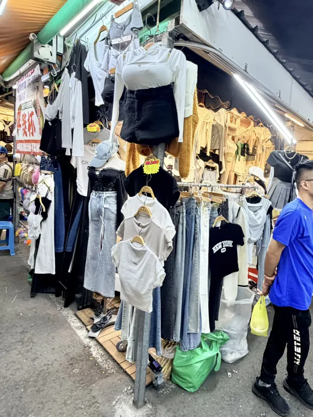 夜市裡的服飾攤位，吊掛著各式衣褲