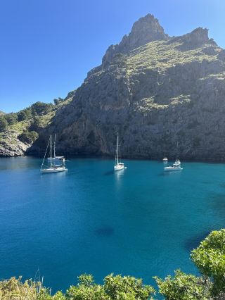 Sail into Paradise at Sa Calobra 🌊🛥️  
Brace yourself—Sa Calobra is an iconic slice of Mallorca, where dramatic mountains plunge into a dazzling turquoise bay. After conquering the nerve-wracking Coll dels Reis pass (682 meters, endless hairpins!), you’ll emerge into a chill beach cove that’s a favorite for luxury yachts and Insta-hunters alike.

🛣️ Recommended Route:  
Take the scenic drive via Coll dels Reis—those twists and turns are not for the faint-hearted! Start early to avoid bus convoys and traffic jams. Once at Sa Calobra, park up (paid lots available) and descend to the pebble beach.  

🏖️ Must-Do Experiences:  
Stroll the coastal path tunneled through cliffs—this leads to Torrent de Pareis, a dramatic canyon, perfect for adventure photos. Swim in crystal-clear waters or just soak in the views of sleek yachts bobbing in the bay.  

📸 Top Photo Spots:  
Snap the classic view at the cliffside tunnel exit, catch the bay at sunrise for softer light, or shoot yacht reflections near the water’s edge. Don’t miss the moody rocks surrounding the Torrent de Pareis mouth.  

⏰ Visiting Tips:  
Arriving early (before 10 AM) is key for easier parking and avoiding crowds. Wear sturdy shoes—the beach is pebbly and trek to the canyon is rocky. Bring snacks and water—options are limited and pricey.  

⚠️ Precautions:  
The road down is steep and super twisty—take it slow, especially if you get carsick. Weather can change fast in the mountains—check forecasts before starting the drive!

#Mallorca  #SaCalobra  #CrystalBay  #DriveAdventure  #TravelTips 