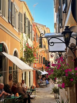Charming Kerkyra: A Slice of Italy on the Greek Island of Corfu 🇬🇷

If you want to truly feel the heartbeat of Corfu, you must spend a day getting lost in the narrow streets of its capital, Kerkyra or Corfu Town. The Old Town is so deeply infused with Venetian charm that it is easy to forget you are actually in Greece.
For the best experience, I highly recommend getting lost in Campiello, which is the oldest neighborhood in the city. Its labyrinth of narrow alleys, tall pastel-colored buildings, and laundry hanging between balconies feels like a living postcard. You should also take time to chase the vibrant pink bougainvillea flowers against the warm, sun-kissed terracotta walls, as they create the perfect aesthetic backdrop for stunning travel photos. While wandering, look up to spot Saint Spiridon Church. You can easily catch glimpses of its iconic red-domed bell tower peeking beautifully through the narrow street openings.

📍 Location Corfu Town, Kerkyra, Greece

To make the most of your visit, here are a few practical tips. First, beat the crowds by arriving either early in the morning before 9:00 AM to enjoy the quiet alleys before the cruise ships arrive, or later in the evening when the golden hour hits and the local cafe lights turn on. Second, make sure to watch your step and wear comfortable walking shoes because the historic streets are paved with old stone and marble, which can be surprisingly slippery. Finally, try some local flavor by skipping the tourist-heavy Liston promenade for a moment and ducking into the quieter side streets to enjoy a refreshing local tsitsibira, a traditional ginger beer, at a hidden café.

I highly recommend dedicating at least one full day to just wandering around without a map. The atmosphere here will make you fall in love instantly.

#Corfu #Greece #CorfuTown #TravelTips 
