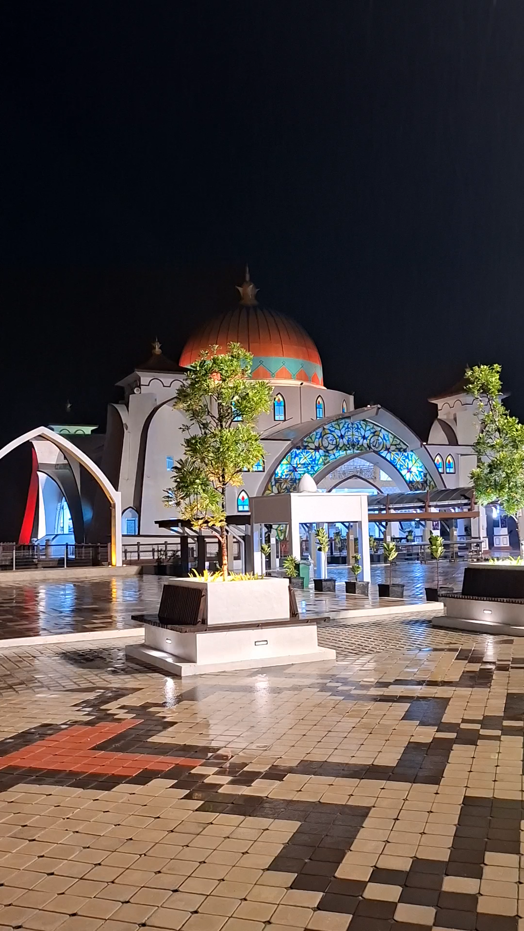 🌙✨ Melaka Straits Mosque — Where Islamic Elegance Meets the Straits of Malacca

Standing gracefully on the waters of the Straits of Malacca, the Melaka Straits Mosque, popularly known as the Floating Mosque, is one of Malaysia’s most enchanting architectural landmarks. Especially at night, when the mosque is illuminated against the dark sky and its lights shimmer across the wet pavement, the entire place creates an atmosphere of peace, beauty, and spiritual serenity.

Located on Pulau Melaka, a man-made island, the mosque was constructed on stilts above the water. When the tide rises, the structure appears to float gracefully on the sea, giving it its famous nickname—the “Floating Mosque.” The mosque was officially opened in 2006 and has since become one of Melaka’s most recognizable modern landmarks.

🕌 A Beautiful Blend of Cultures

The architecture of Melaka Straits Mosque reflects a fascinating combination of Malay and Middle Eastern Islamic influences. Its elegant golden-toned dome, graceful arches, decorative details, and distinctive towers create a harmonious visual identity. The design also reflects elements of Malaysian architectural traditions, making the mosque both a place of worship and an impressive cultural landmark.

The mosque’s position beside the sea makes it particularly spectacular during sunset, high tide, and nighttime. Reflections of the illuminated building on the water create a magical scene that attracts photographers and travellers from around the world.

🌏 Melaka — A City Shaped by History

The mosque is situated in Melaka, a city whose history is deeply connected with the Straits of Malacca, one of the most important maritime trade routes in Southeast Asia.

Melaka was established in 1403 and developed into a major international trading centre, attracting merchants and travellers from many parts of Asia and beyond. Over the centuries, Portuguese, Dutch, and British influences left their marks on the city’s architecture, traditions, cuisine, and cultural identity. Melaka was recognized as a UNESCO World Heritage Site in 2008.

🎭 A Meeting Place of Cultures

One of the most remarkable features of Melaka is its multicultural heritage. Malay, Chinese, Indian, Portuguese, Dutch, and other cultural influences have interacted here for centuries.

This cultural diversity can be seen in Melaka’s historic buildings, traditional food, religious sites, festivals, handicrafts, and especially its famous Peranakan (Baba-Nyonya) culture, which represents a unique fusion of Chinese and Malay traditions with additional European influences.

A journey through Melaka therefore feels like travelling through different chapters of Southeast Asian history—where old traditions continue to live alongside modern Malaysian life.

🌧️ The Beauty of a Rainy Night

The scene captured in this video has a special charm. Rain-covered pathways reflect the colourful lights surrounding the mosque, while the illuminated dome and arches stand beautifully against the night sky.

For a traveller, moments like this are more than ordinary sightseeing. They are memories created through light, rain, architecture, history, and atmosphere—a quiet reminder of why travelling is such a beautiful way to discover the world.

Melaka Straits Mosque is not simply a mosque; it is a symbol of faith, architecture, maritime heritage, and Malaysia’s multicultural identity.

📍 Location: Pulau Melaka, Melaka, Malaysia
🕌 Also known as: Melaka Straits Mosque / Floating Mosque
🌊 Famous for: Its waterfront setting and floating appearance at high tide
🏛️ Opened: 2006
🇲🇾 Region: Historical Melaka, Malaysia

“When the rain falls over Melaka, the Floating Mosque seems to rise from the water like a luminous jewel—where faith meets the sea and history meets the present.”

#Melaka  #MelakaStraitsMosque  #FloatingMosque  #MasjidSelatMelaka  #Malaysia  #VisitMelaka  #MalaysiaTravel  #TravelPhotography  #TravelStory  #IslamicArchitecture  #CulturalHeritage  #StraitsOfMalacca  #Wanderlust  #BeautifulDestinations  #NightPhotography 
