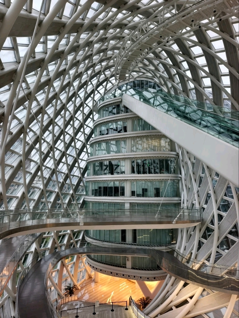 Beijing Phoenix Centre adalah salah satu contoh arsitektur modern paling menakjubkan di kota ini, melambangkan inovasi dan keanggunan. Terletak di Distrik Chaoyang, Beijing, landmark futuristik ini dirancang oleh arsitek terkenal dunia Zaha Hadid. Struktur melengkung dan mengalirnya menyerupai sepasang sayap yang sedang bergerak, mewakili kebebasan, kreativitas, dan semangat kemajuan. Bangunan ini berfungsi sebagai kantor pusat Phoenix TV dan dilengkapi dengan teknologi hijau canggih, termasuk kaca hemat energi dan sistem pencahayaan pintar. Di dalamnya, ruang terbuka dan koridor spiral menciptakan rasa gerakan dan harmoni, memadukan seni dengan teknologi. Pada malam hari, bangunan ini bersinar indah dengan lampu LED, memantul di air sekitar seperti seekor phoenix yang bersinar bangkit dari bumi. Pengunjung sering terpesona oleh desain uniknya, menjadikannya tempat populer bagi fotografer dan pecinta arsitektur. Beijing Phoenix Centre berdiri sebagai simbol kuat dari keseimbangan Tiongkok modern antara keindahan, inovasi, dan budaya.