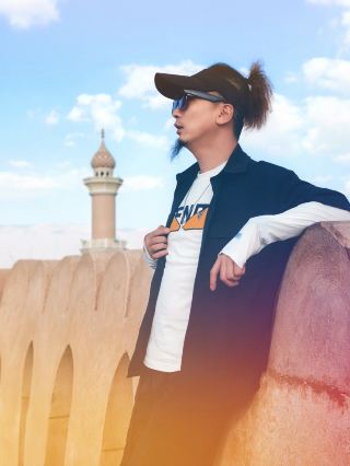 Горы и древние города Омана: встреча с тысячелетней мудростью сквозь складки времени

Когда колеса катились по красным песчаным дорогам внутренних районов Омана, а силуэт города постепенно скрывался за охристыми горами, я прибыл к желтовато-глиняным постройкам деревни Мисфат Абриан. Это путешествие, сочетающее пеший туризм и знакомство с культурой, позволило мне прикоснуться к мудрости жизни, которая пережила тысячу лет в горах и древних городах Омана. Прогуливаясь по улицам и переулкам Мисфат Абриана, я ощущал, как мощеные дорожки под ногами отшлифовываются временем, а глинобитные дома по обеим сторонам горы, белые оконные рамы которых мягко мерцают на солнце, были построены прямо у подножия горы.

Самым поразительным была ирригационная система Фарадж, скрытая среди улиц и переулков. Эта жизненно важная система, занесенная ЮНЕСКО в список нематериального культурного наследия, состоит из искусственных подземных каналов и открытых рвов, доставляющих талую воду с высокогорных ледников в каждый уголок деревни. Трудно представить, что в этой засушливой местности древние могли использовать свою мудрость для создания такой сложной системы водоснабжения, превратив пустыню в оазис. Это не только инженерное чудо, но и свидетельство оманской философии выживания, философии почтения и гармонии с природой.

Покинув горную деревню, мы поехали в Низву, культурный центр во внутренней части Омана, место, наполненное яркими традиционными воспоминаниями. Одна из самых известных исторических крепостей Омана величественно возвышается в центре города. Поднимаясь на самую высокую точку крепости, перед вами открывается весь город Низва: его красные черепичные крыши прекрасно контрастируют с зелеными деревьями, а вдали простираются бесконечные горы. Внутри музея форта выставлены старинное оружие, одежда и предметы домашнего обихода, а выцветшие фотографии документируют историческую эволюцию Омана.

Когда-то оплот против внешних врагов, теперь он служит хранилищем исторической памяти, свидетельствуя о трансформации Омана от межплеменных конфликтов к мирному развитию.

Мудрость ирригационной системы Фарадж, оживленная атмосфера рынков Низвы и внушительное присутствие древней крепости создают неповторимое очарование Омана. Как путешественник, постоянно находящийся в дороге, я видел бесчисленные пейзажи. В Омане я почувствовал тепло и глубину различных культур и встретил мудрость и красоту, не стертые временем.