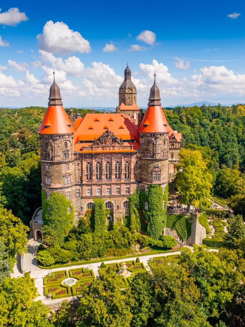 The highlighted building is Książ Castle (Zamek Książ), famously known as the "Pearl of Lower Silesia," located in Wałbrzych, Poland. Built between 1288 and 1292 by Duke Bolko I the Strict, it stands as the third-largest castle in Poland and the largest fortress in the Silesia region.
The castle is spectacularly situated on a steep rock cliff within the protected Książ Landscape Park, overlooking the Pełcznica River Gorge.
For over 400 years, the castle belonged to the prominent Hochberg family, who transformed it from a medieval fortification into a sprawling, eclectic palace boasting over 400 rooms.Architectural Eclecticism: Due to centuries of restructuring, it beautifully fuses Gothic, Renaissance, Baroque, and Neo-Romanesque styles.World War II Secrets: Seized by Nazi forces during the war, the castle was heavily modified to serve as a headquarters for Adolf Hitler. It hides a mysterious network of underground tunnels carved deep into the rock as part of the top-secret Project Riese.
 Terraced Gardens: The lush manicured lawns shown in the foreground span 14 distinct terraces, designed by English gardeners to drape elegantly down the cliffside.The Underground Tunnels: Visitors can take a dedicated guided route to explore 1.5 kilometers of concrete-reinforced wartime tunnels beneath the estate.The Palm House (Palmiarnia): Located just a short distance from the fortress, this historic greenhouse is filled with exotic, tropical plants.Sightseeing Hours: Generally open daily from 9:00 AM to 6:00 PM during high season (April to October), with slightly reduced hours in winter.