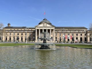 Wiesbaden, located in southwestern Hesse, Germany, is the capital of the state and one of Germany's most famous spa cities. Nestled on the southern slopes of the Taunus Mountains and the east bank of the Rhine River, it faces Mainz across the river. With a population of approximately 307,000, it is the second largest city in Hesse and a major administrative, economic, and cultural center of the Rhine-Main region. Wiesbaden boasts a long history, renowned for its spas since Roman times, and developed into a leading European spa resort in the 19th century. Today, the city retains its distinctive spa town character. The famous Kurhaus is located in Wiesbaden.