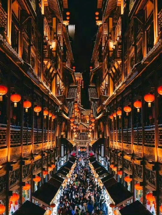 Hongya Cave isn’t just a destination—it feels like stepping into a glowing memory carved into the mountainside.

By day, it clings quietly to the cliff above the Jialing River, layered like an ancient wooden village suspended in time. But as dusk falls, everything transforms. Lanterns ignite one by one, golden light spilling across the stacked terraces until the entire structure becomes a cascading river of fireflies against the Chongqing skyline. From across the bridge, it looks almost unreal—like a scene lifted straight from a fantasy film.

Wander through its multi-level walkways and you’ll find narrow alleys filled with sizzling street food, handmade trinkets, and the smell of hot pot drifting through the air. Step out onto the upper decks for sweeping views of the river where skyscrapers reflect in the water like molten glass.

📍 Tips

Best time to visit: 6:30–9:30 PM for full illumination magic

Photo spot: Qiansimen Bridge opposite the complex for the classic skyline shot

How to get there: Metro Line 2 → Linjiangmen Station, then a short walk downhill

Hongya Cave isn’t just something you visit—it’s something you watch light up inside your memory long after you leave.