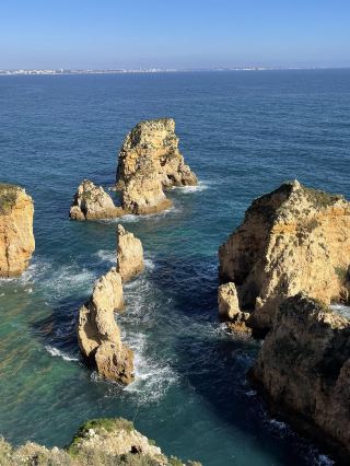 🇵🇹 Ponta da Piedade | Lagos, Portugal 🌊💙

Another stunning seaside viewpoint in Portugal that will make you stop and admire it.

Ponta da Piedade is located in Lagos, in southern Portugal, in the Algarve region. It's famous for its golden cliffs and uniquely shaped rock formations scattered across the sea. Some are towering structures, while others are smaller rock peaks, eroded by the sea into beautiful natural shapes.

What makes this place so special is the gradient of color from clear blue to deep blue. Looking down from the top of the cliffs, you can see white waves crashing against the rocks below, contrasting beautifully with the golden yellow of the cliffs – a scene so stunning you barely need any editing in photos! 📸

There are several walking paths and viewpoints along the cliff face, allowing you to stroll along and enjoy the scenery. Each spot offers a different perspective; some show rocks standing in the sea, while others reveal the long stretch of cliffs extending into the distance. On a clear day with good weather, the view is absolutely breathtaking.

Another thing I love is the atmosphere of the sea here; it's not just the beauty of the water. But there's also the sound of the waves, the wind, and the grandeur of nature that makes you want to spend a long time there.

If you're planning a trip to Lagos, I recommend adding Ponta da Piedade to your list, especially during the morning or evening when the sunlight hits the cliffs, showcasing the beautiful colors of the rocks. Wear comfortable walking shoes and be careful around the edge of the cliff.

It's another incredibly charming place in Portugal. You don't need to do a lot of activities; just walking along, enjoying the view, gazing at the sea, and taking photos is enough to make it worthwhile. 🩵

📍 Ponta da Piedade, Lagos, Algarve, Portugal 🇵🇹

#PontaDaPiedade #LagosPortugal #Algarve #Portugal #TravelPortugal #PortugalTravel #SelfGuidedPortugalTrip #EuropeTravel #BeachTravel