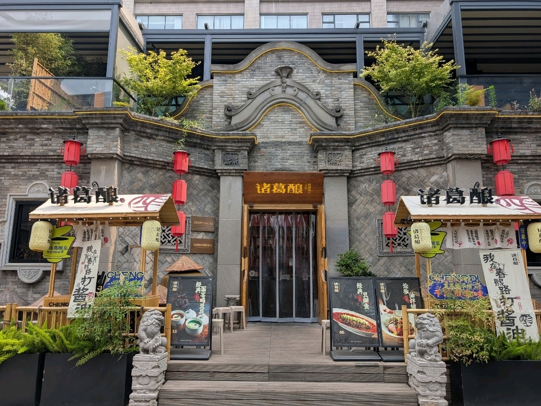 If you are looking to savour Chengdu cuisine in a setting that is a little more special, 诸葛酿 is definitely worth a visit. Located along the bustling Chunxi Street, this themed restaurant stands out with its striking, grand exterior—complete with a short stairway leading up to its entrance. Just follow your map and you won’t miss it.

As soon as we stepped inside, we were greeted by an impressive towering wall of preserved jars that stretches from the second floor all the way down to the first. It is quite the sight and sets the tone for what’s to come. We chose to dine on the second floor to enjoy a view overlooking the street below.

The menu is extensive, and we took the chance to try dishes we had never encountered in Singapore—because why not, right? One of the highlights was their signature Guoba Chicken, served in a heated wooden jar. At first, we did not realise there was a ‘correct’ way to eat it—we eagerly started munching on the crispy rice (Guoba) before the sauce arrived. A waiter rushed over, slightly panicked, to stop us and explained that the rich chicken-and-pork gravy needed to be poured over the rice while it was still sizzling hot. Slightly embarrassing, but a fun memory nonetheless!

Another dish that surprised us was something that looked like a sweet green bean kueh. We assumed it was a dessert, but biting into it revealed a savoury pork filling—it was actually a dim sum dish in disguise. An unexpected twist that made it all the more memorable.

But the standout for me was the fried chicken dish topped with aromatic fritters and a generous amount of chilli flakes. Think 辣子鸡, but elevated—spicy, crispy, and packed with flavour. Hands down, the best version I have had!

All in all, 诸葛酿 offers great food, a vibrant atmosphere, and reasonable prices. Whether you're a fan of Sichuan cuisine or just curious to explore, this is a spot you shouldn’t miss when visiting Chengdu.

